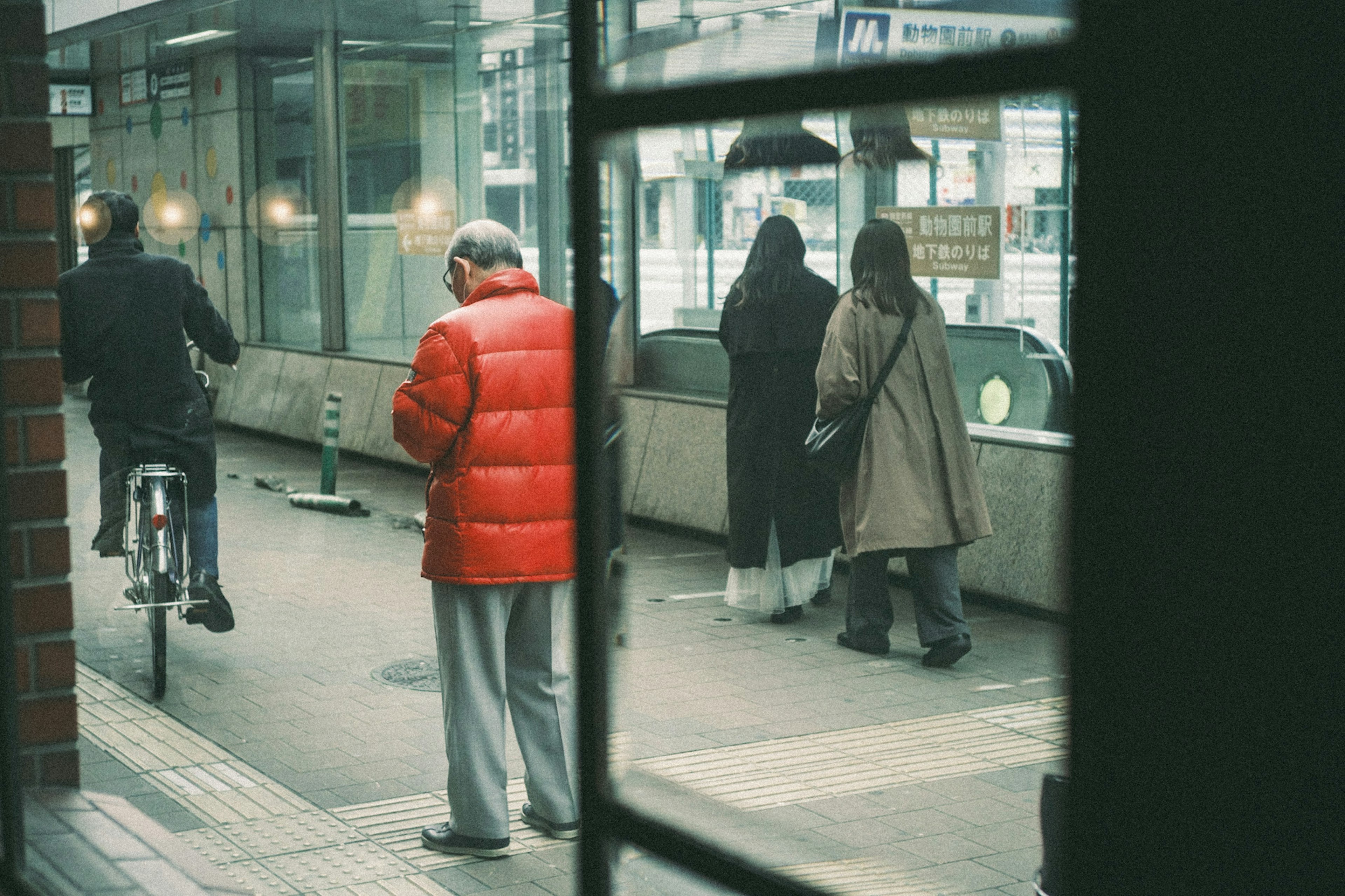 Hombre con chaqueta roja y otras personas esperando en un entorno urbano