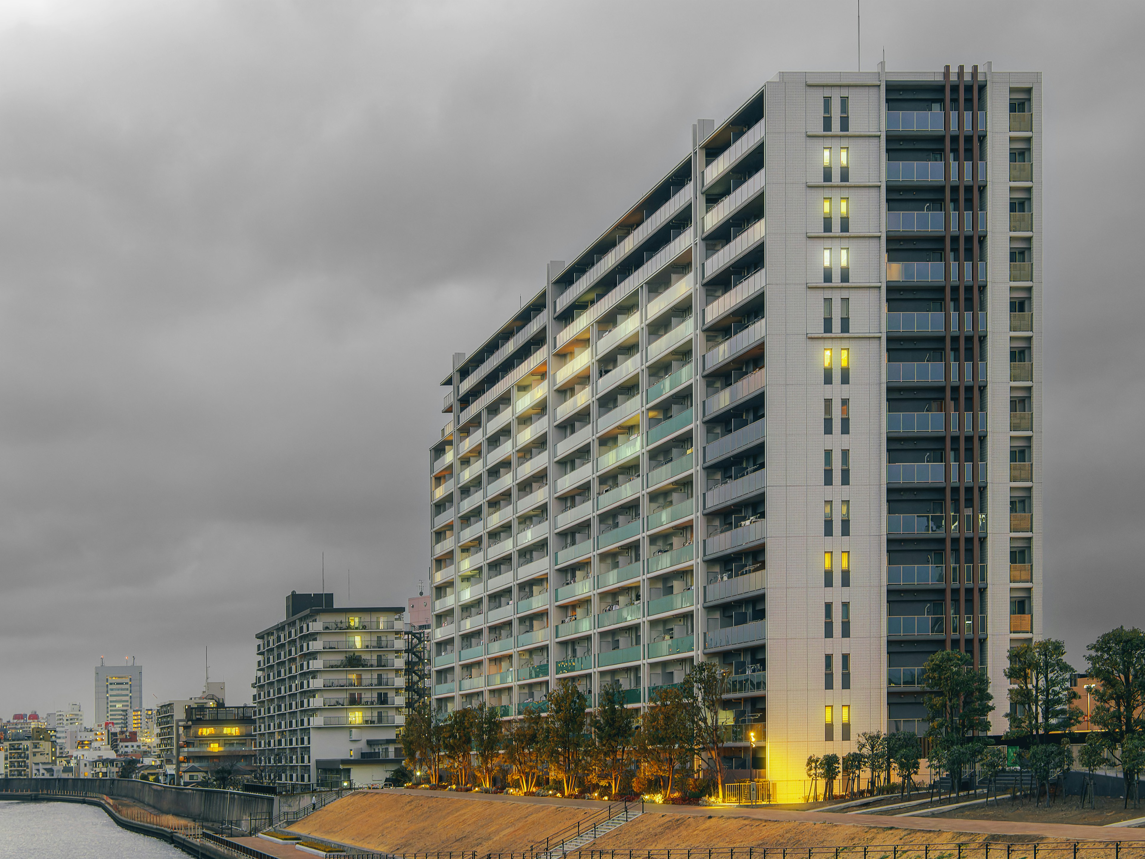 High-rise building at night with gray clouds and illuminated windows