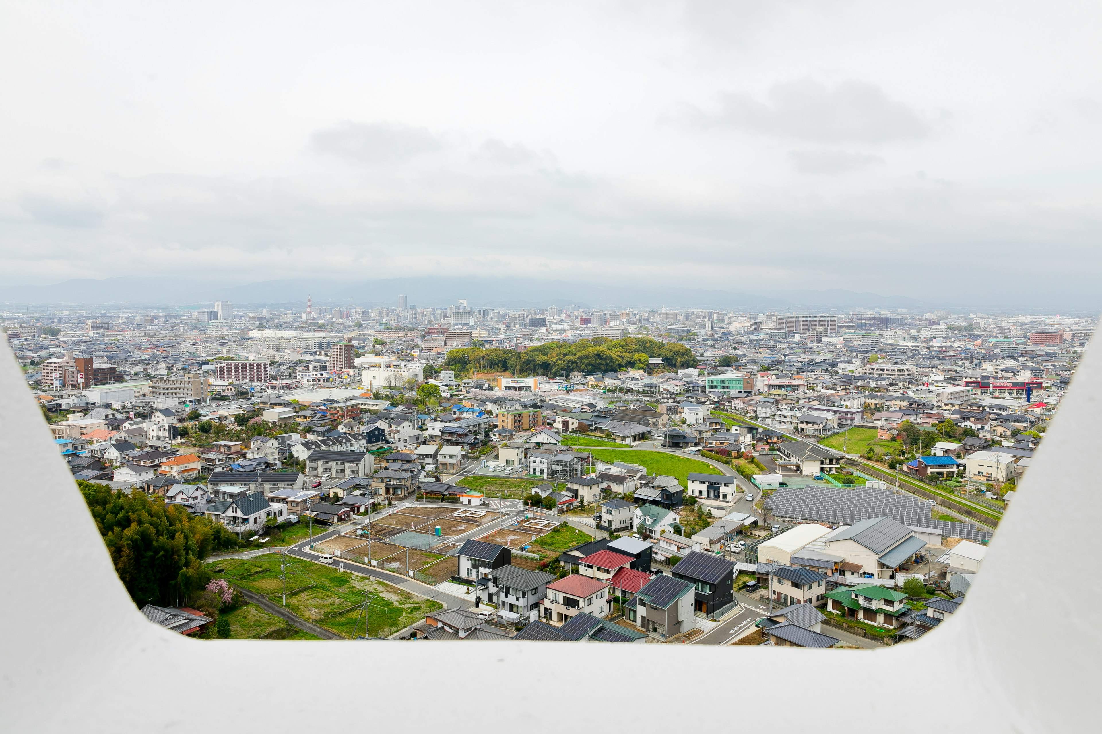 白いフレームの外に広がる都市の風景 緑の丘と住宅が見える