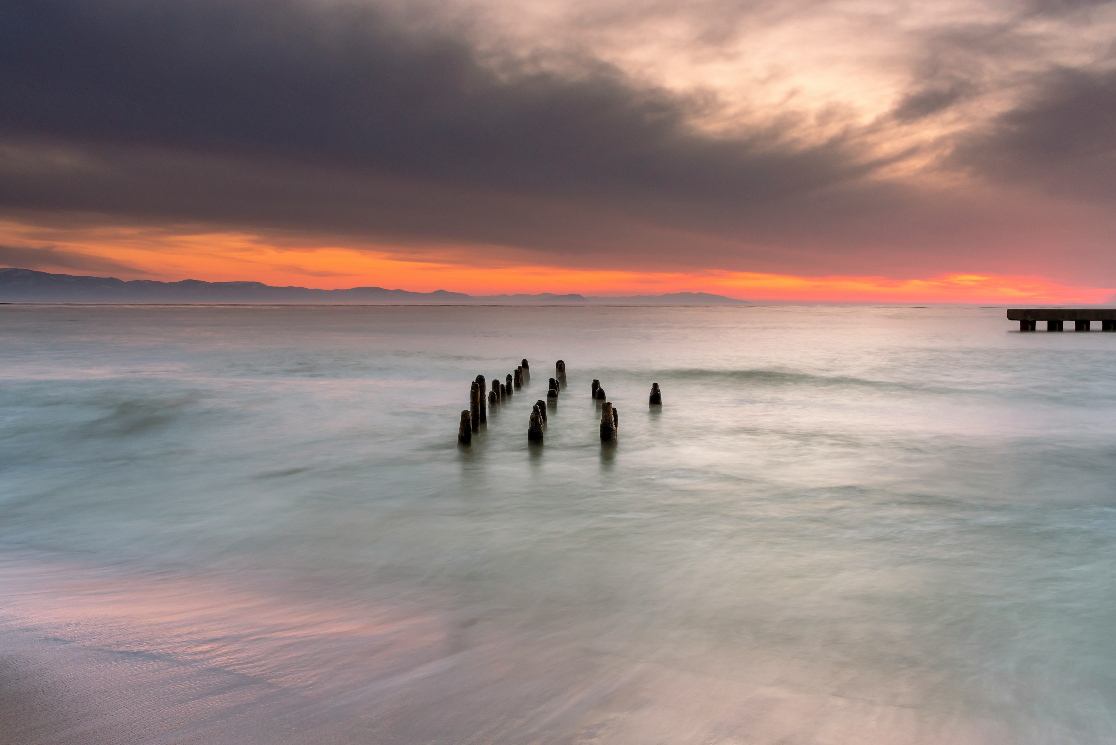 Seascape featuring a sunken pier and vibrant sunset