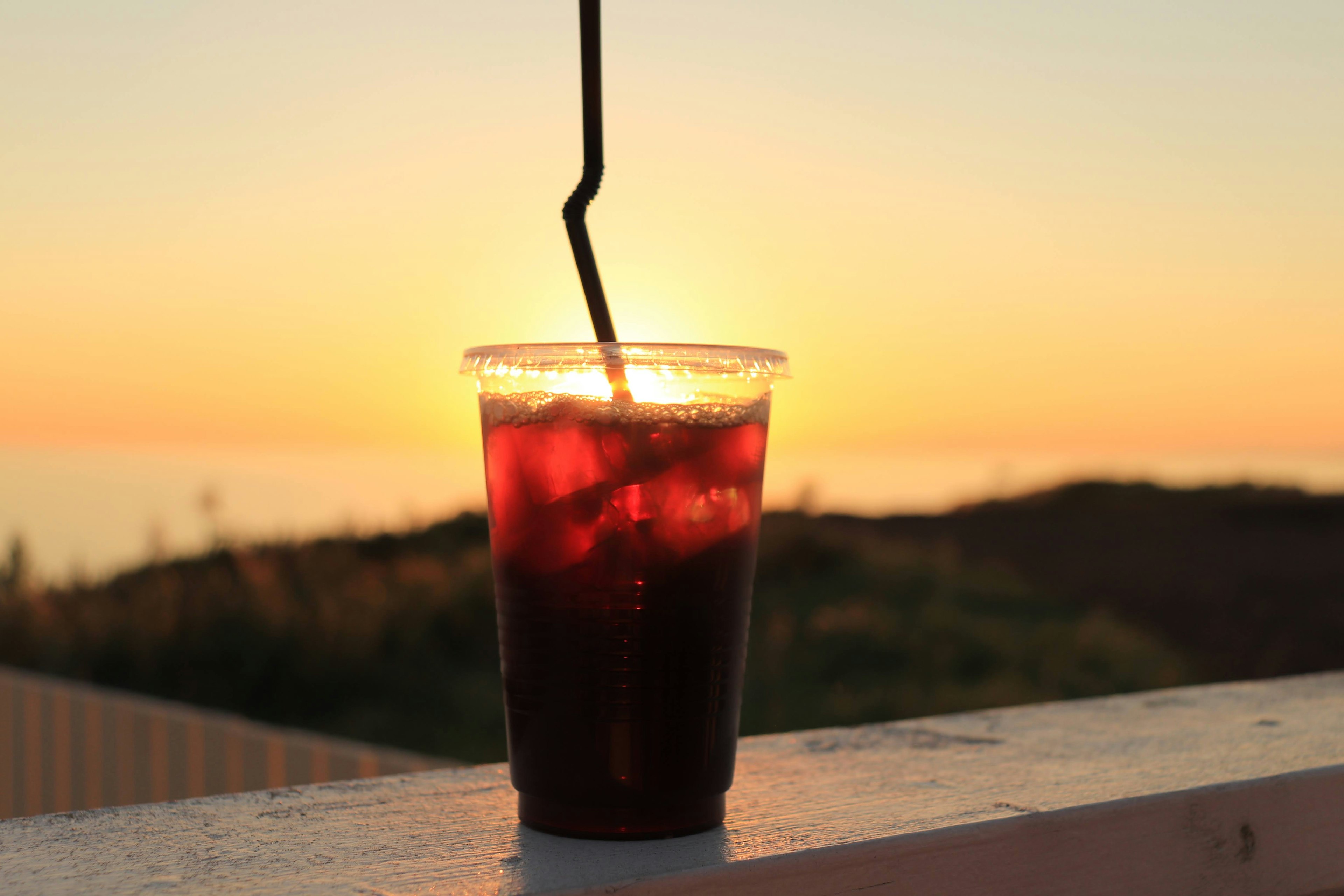 Becher mit eisgekühltem Getränk vor einem Sonnenuntergang