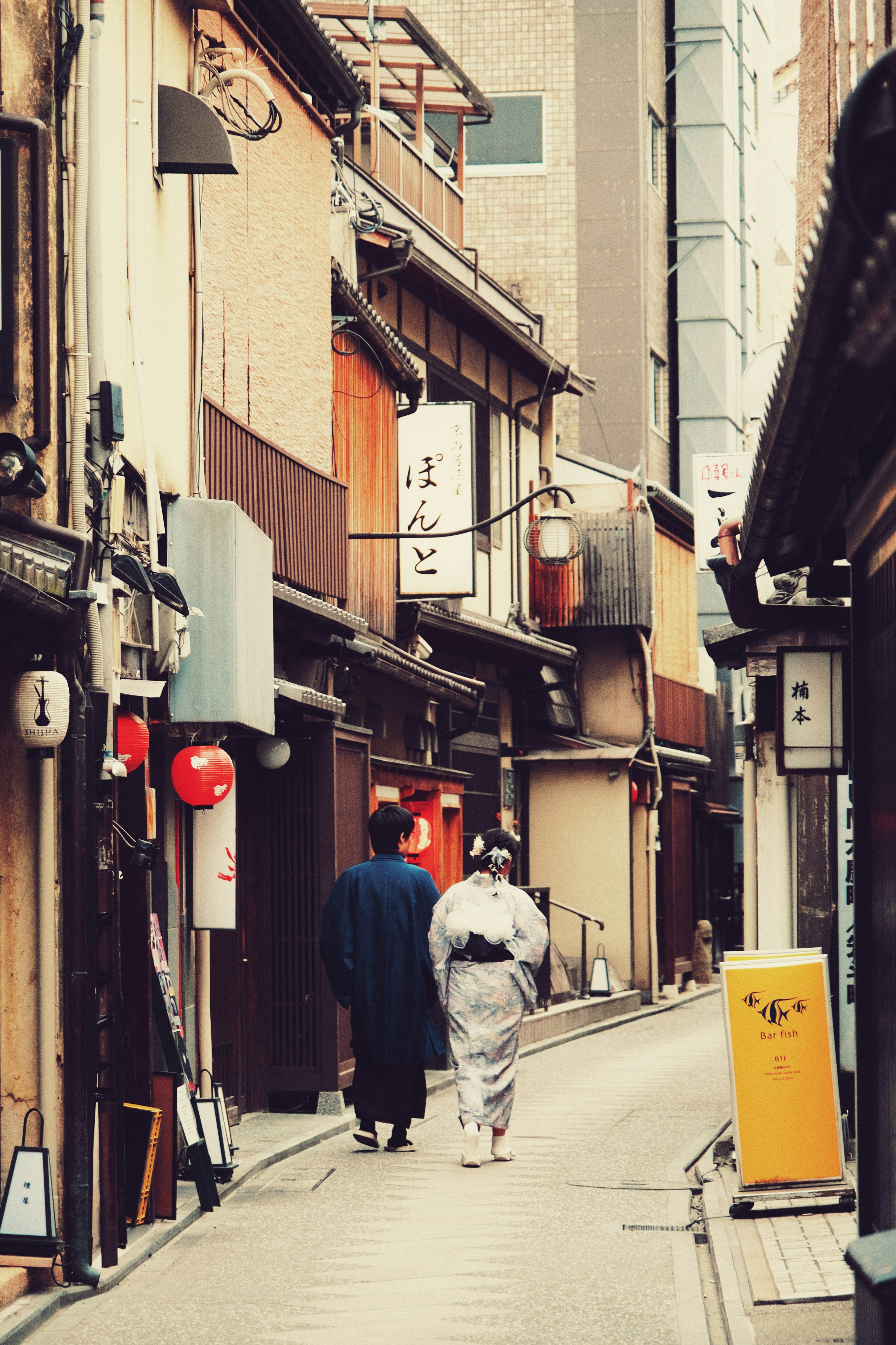 A man and woman in traditional clothing walking down a narrow alley