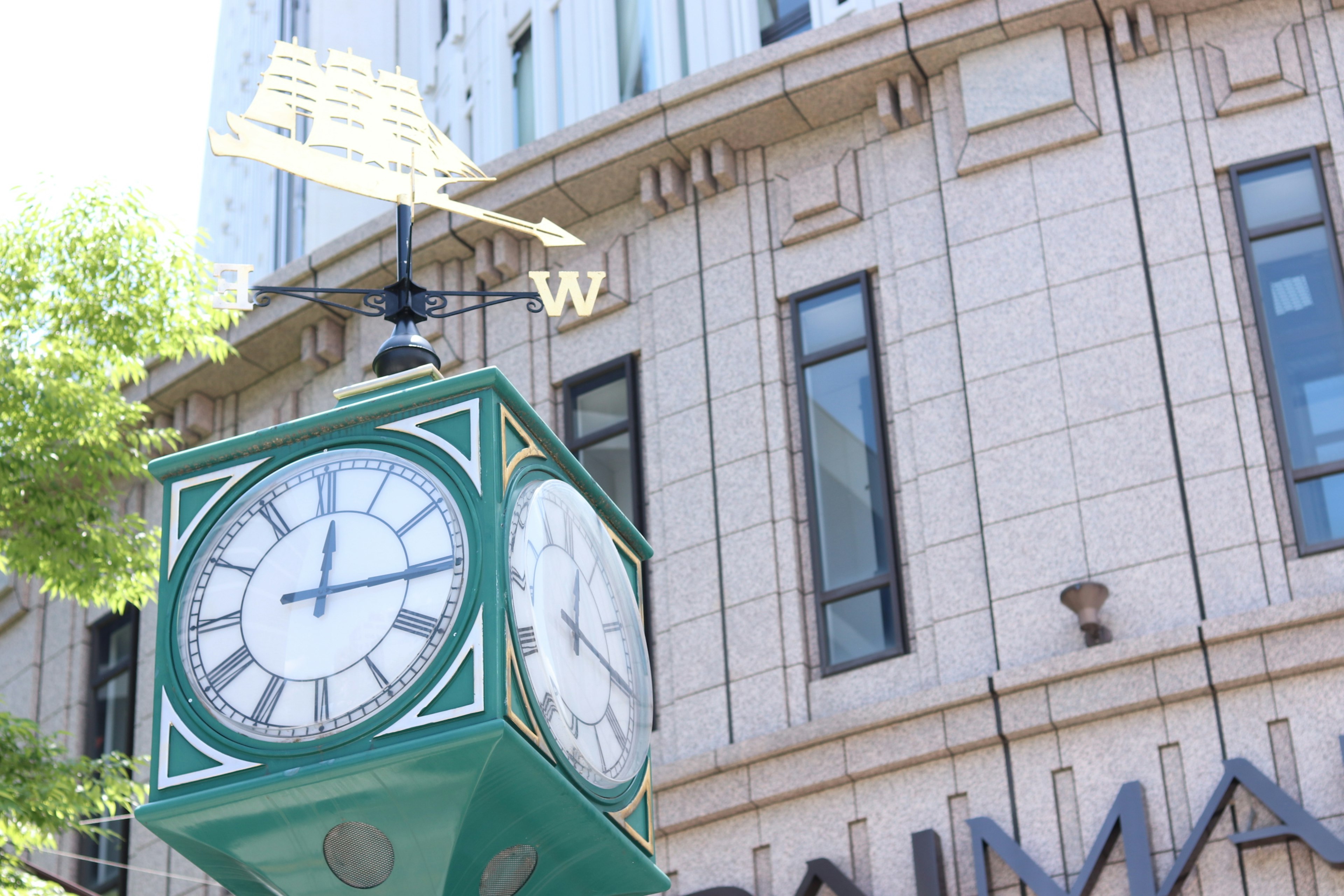 Green clock tower stands in front of a building