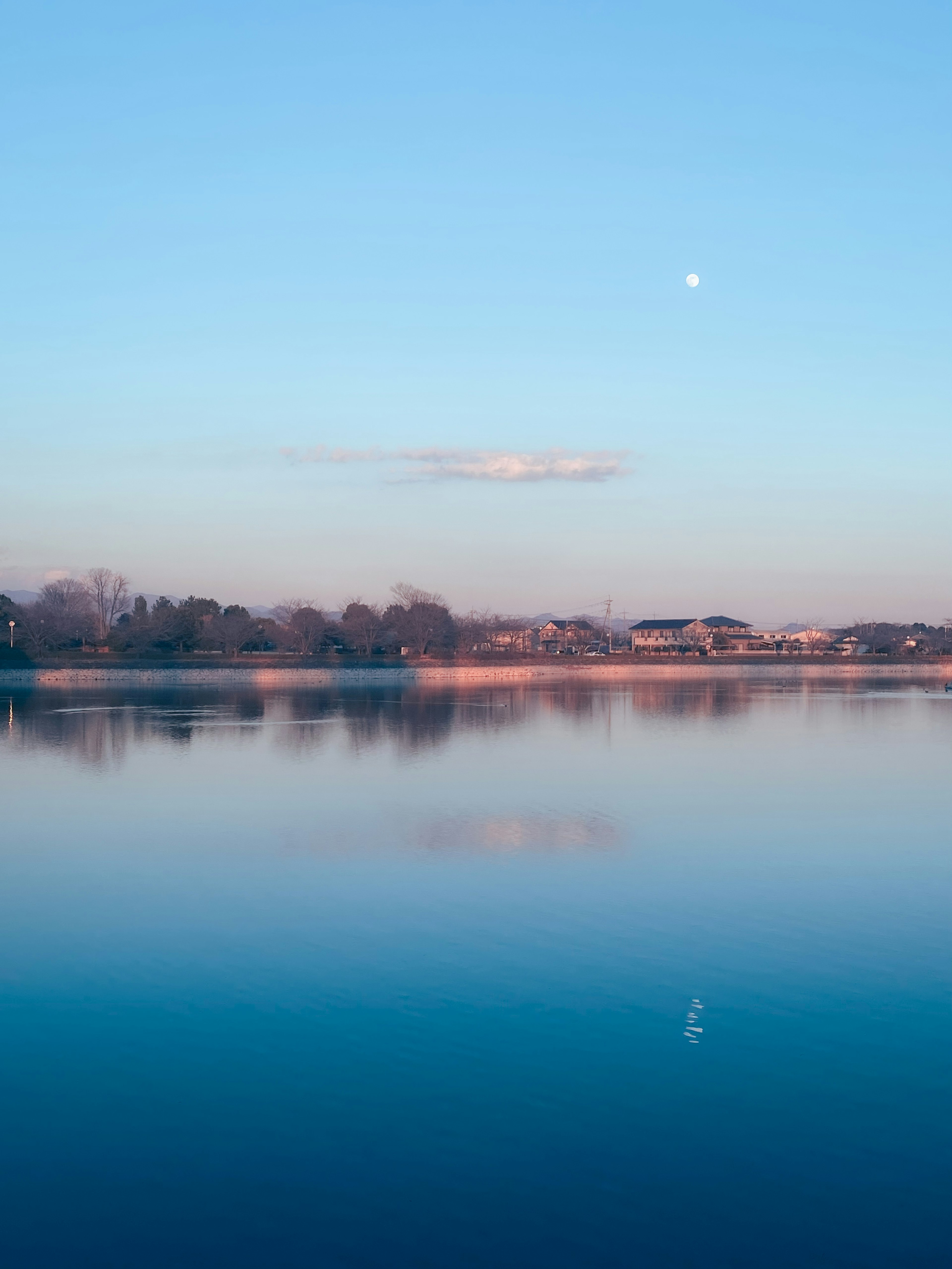 Vue paisible sur le lac avec ciel bleu Lune visible et nuages doux présents