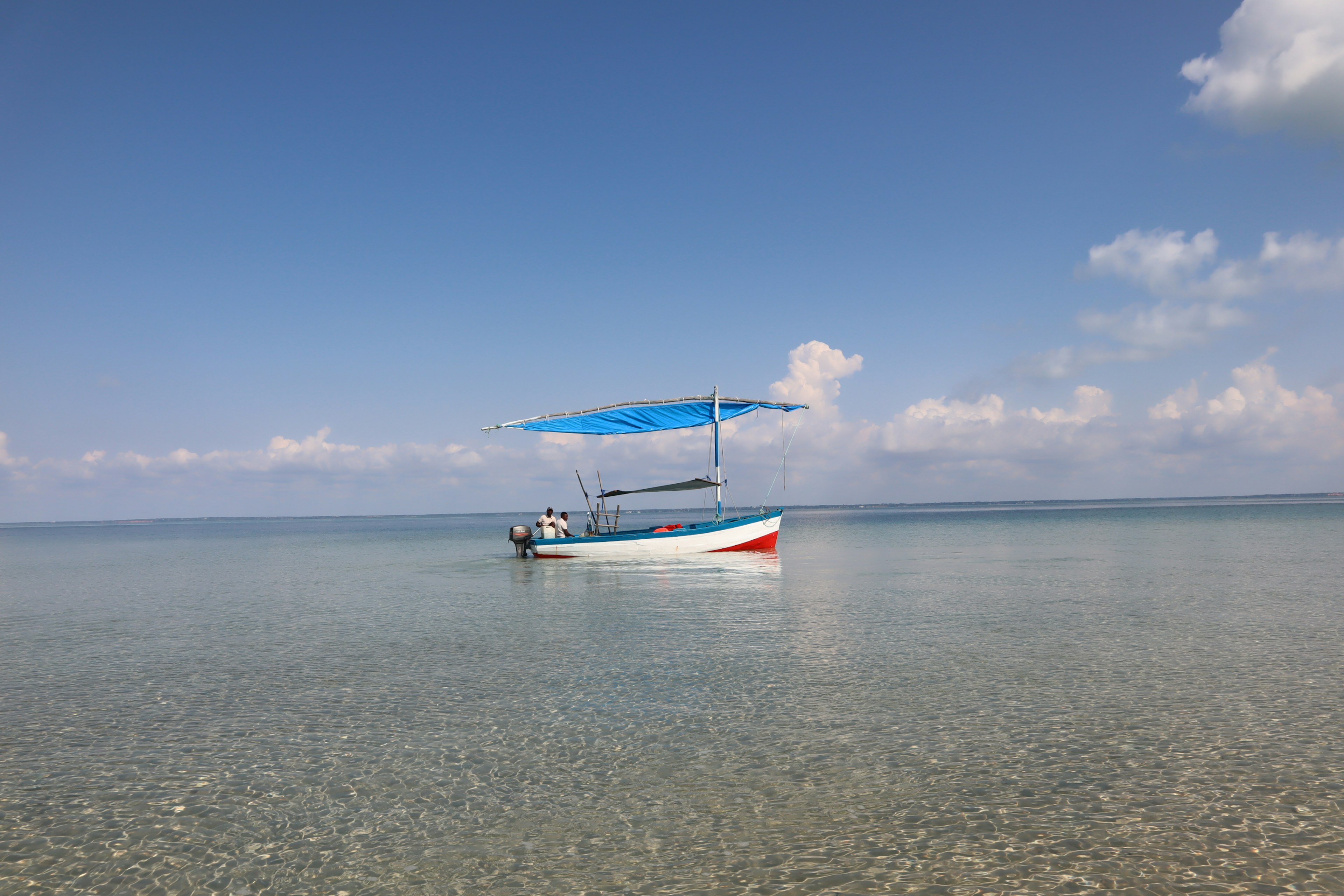 Un pequeño barco flotando en aguas tranquilas bajo un cielo azul claro