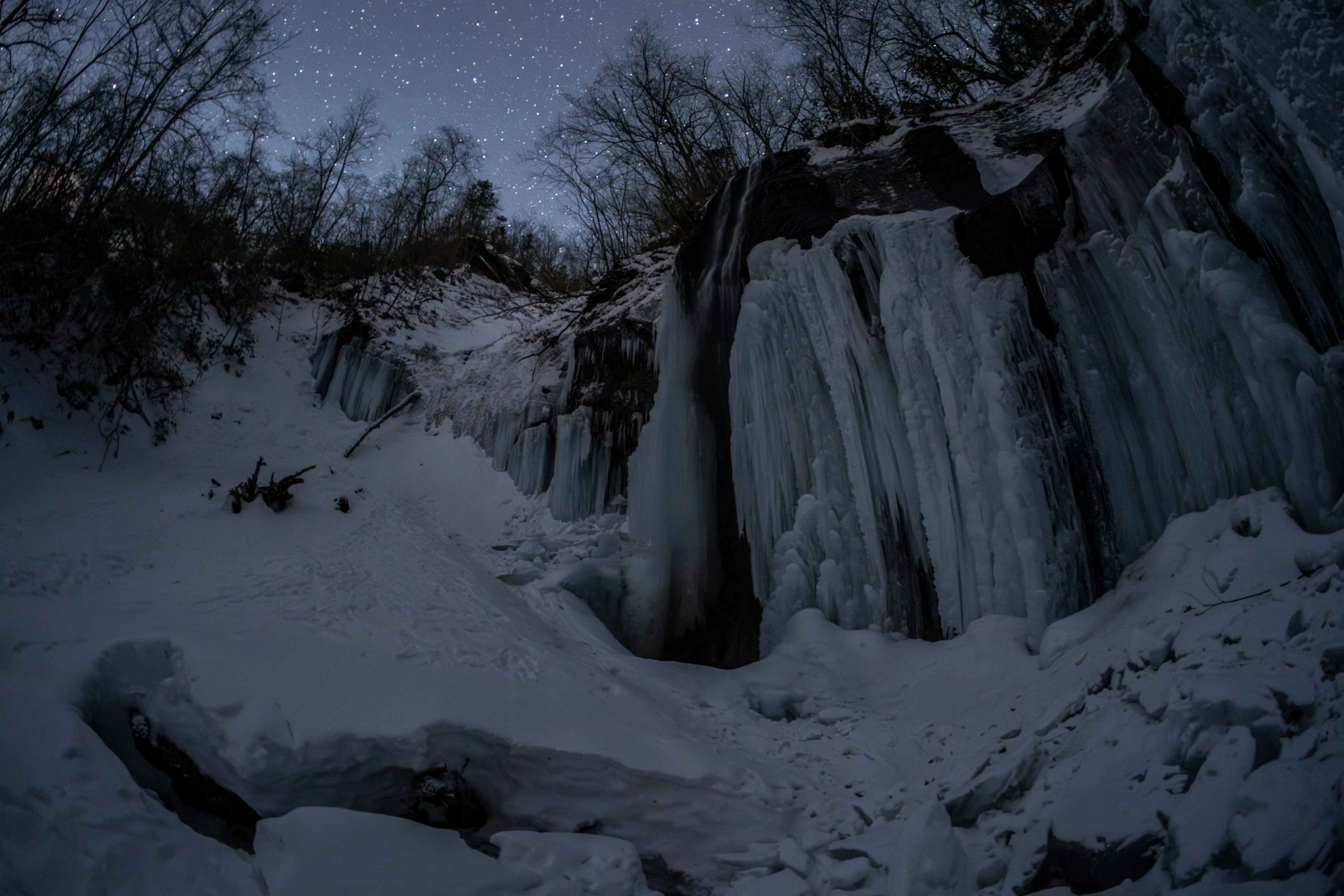 氷の滝と雪に覆われた風景 夜空には星が輝いている