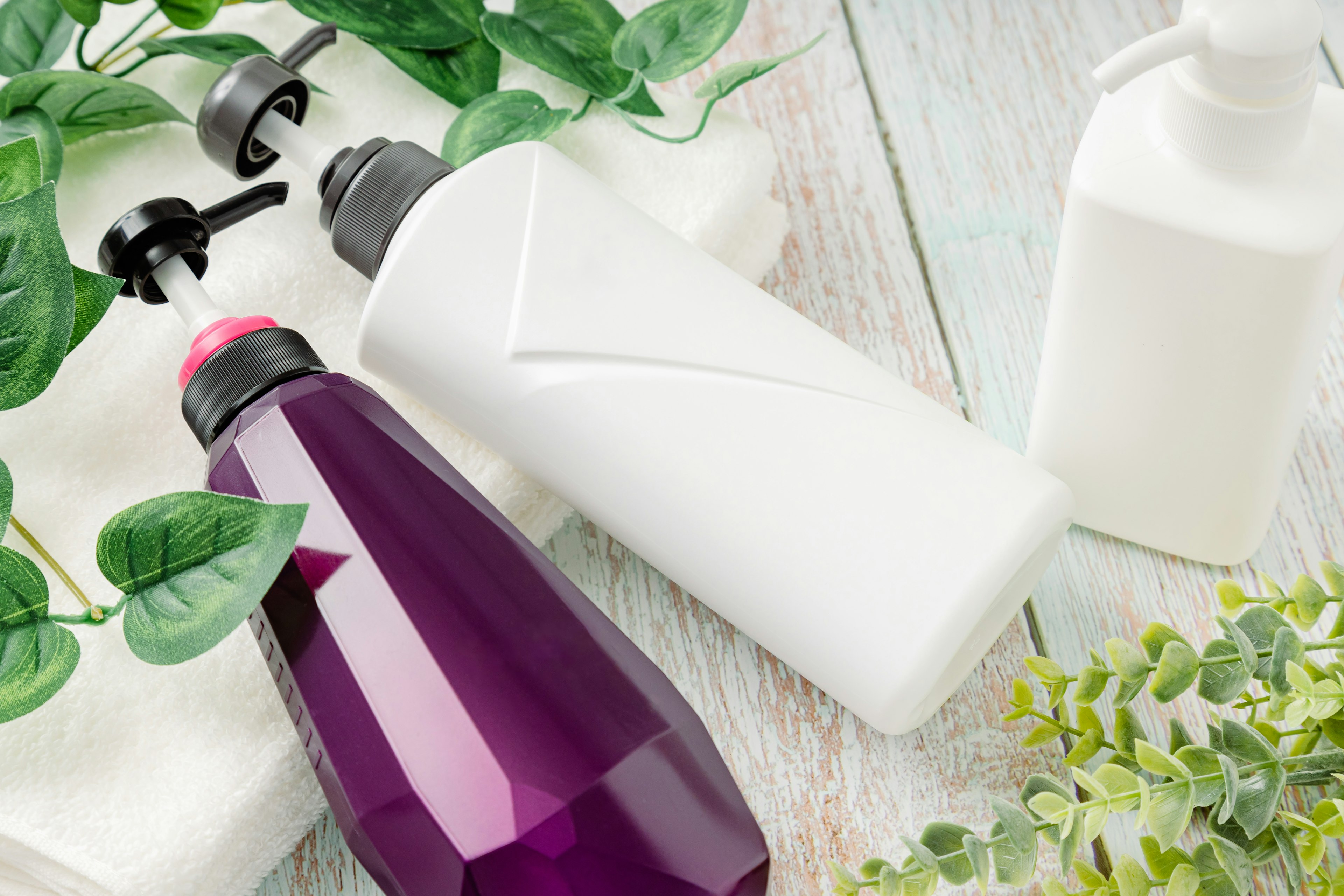 Image of purple and white bottles surrounded by green leaves