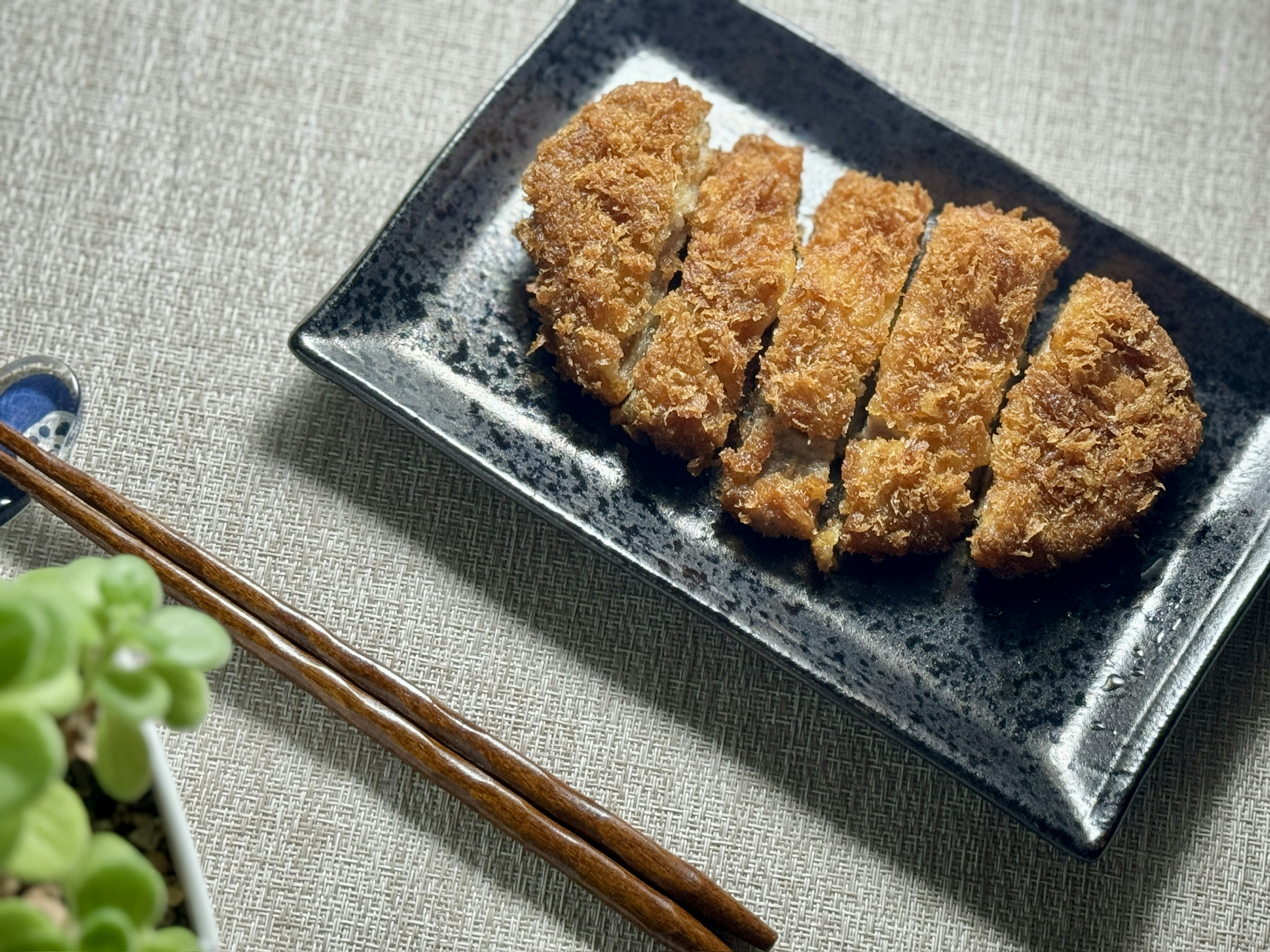 Crispy tonkatsu sliced and served on a black plate