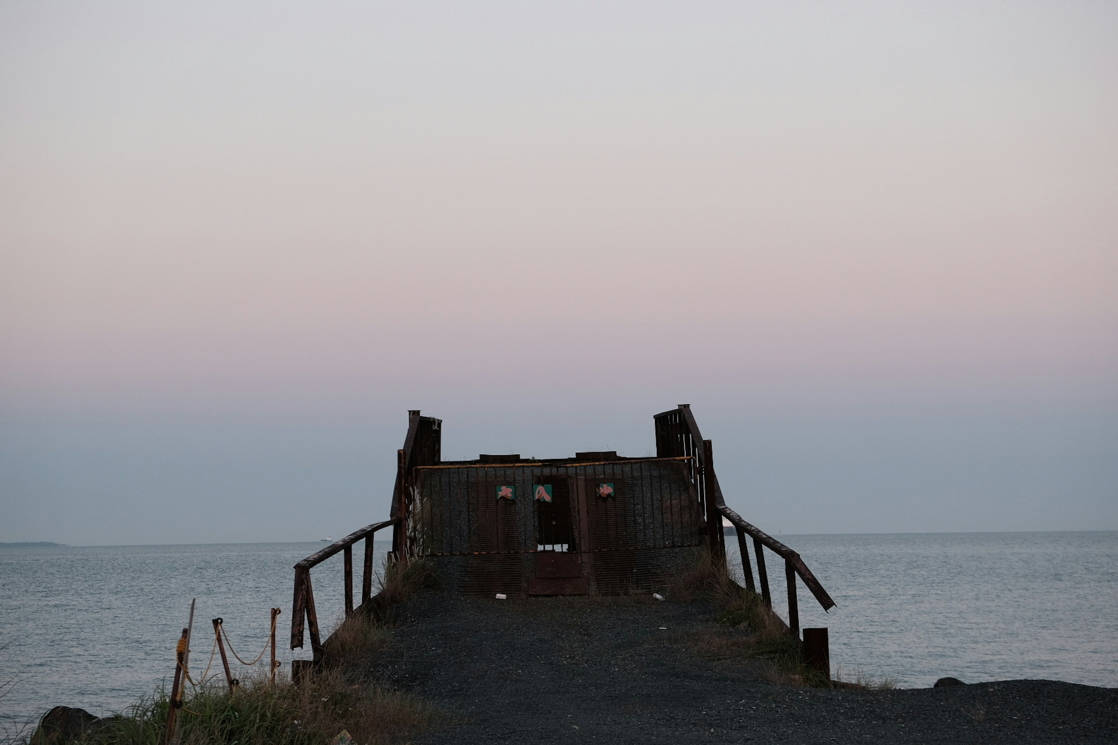 Silhouette di un vecchio molo che si affaccia sul mare con un cielo crepuscolare morbido