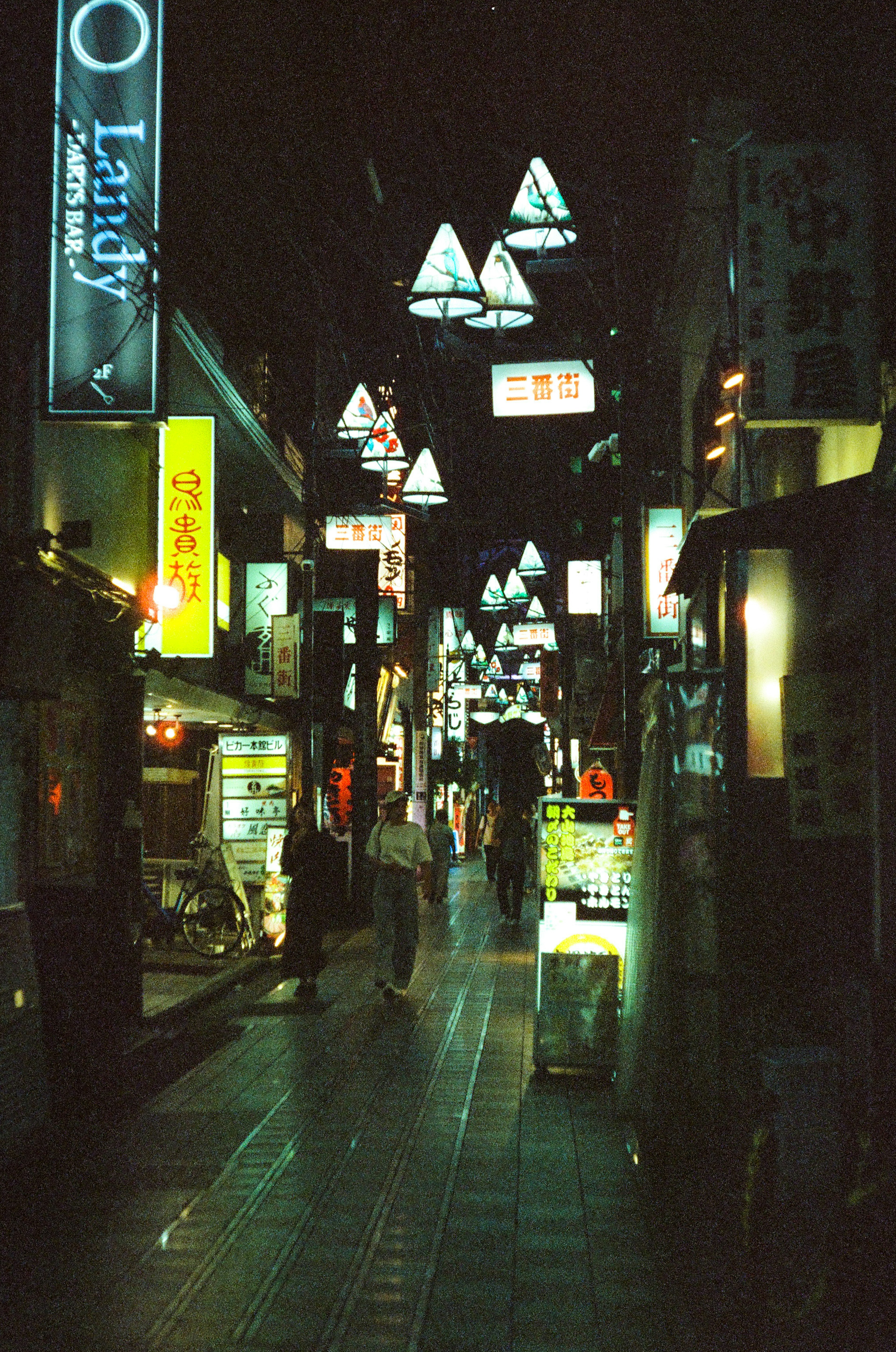 夜间街道场景，三角形灯光和霓虹招牌照亮小巷