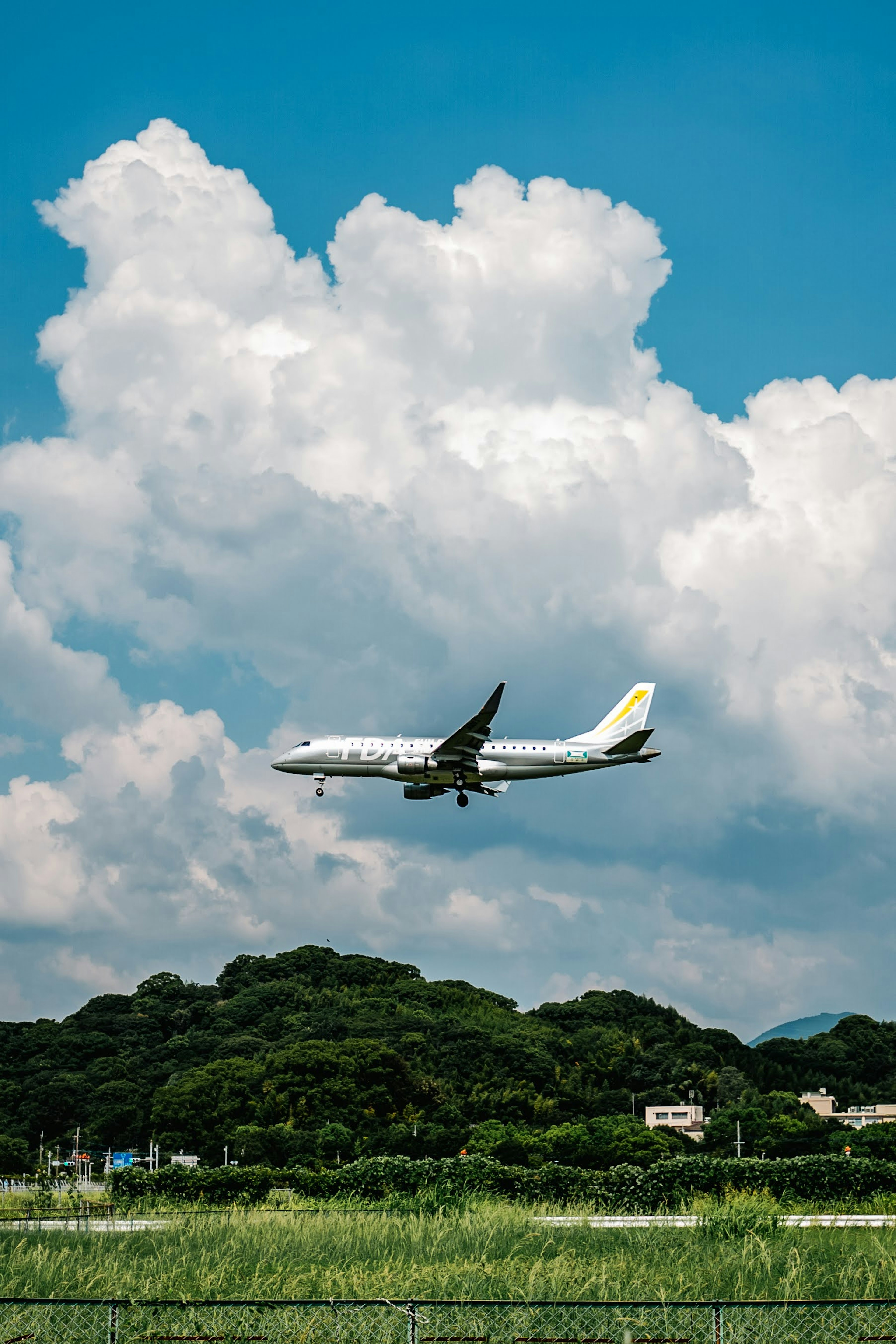 Passenger plane flying near clouds under blue sky