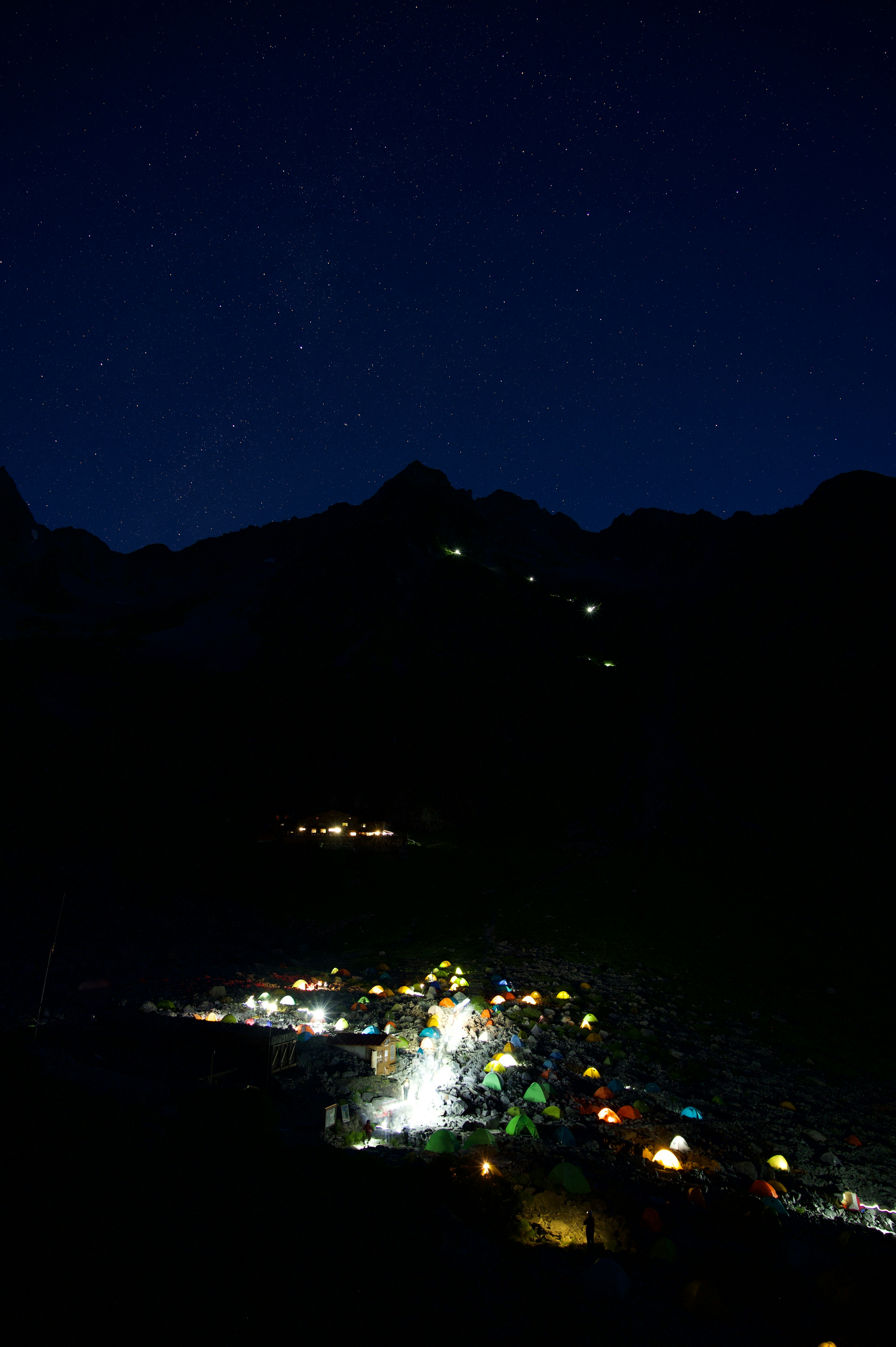 Villaggio illuminato di notte sotto un cielo stellato con montagne