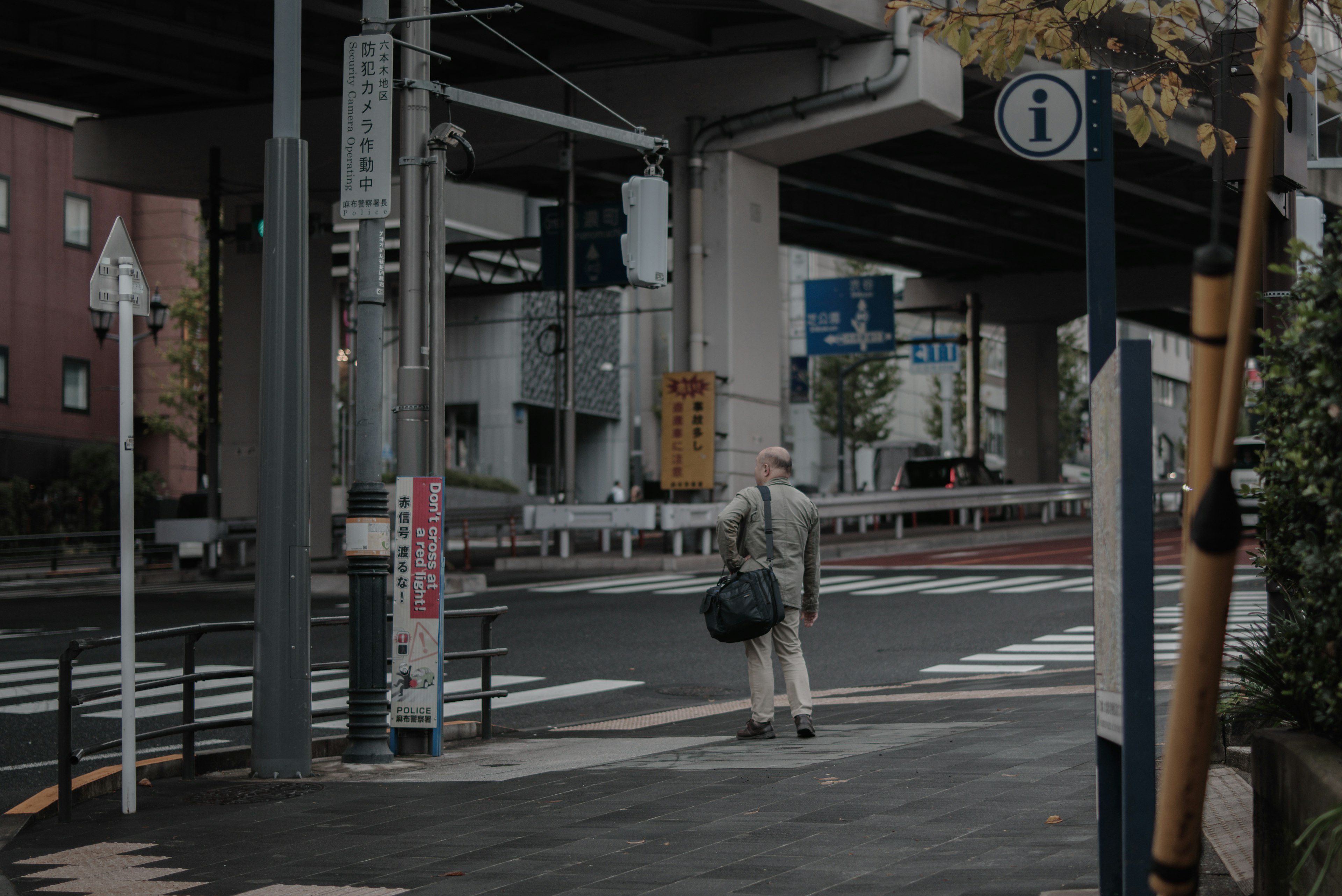 Homme attendant à l'intersection sous un viaduc avec peu de piétons