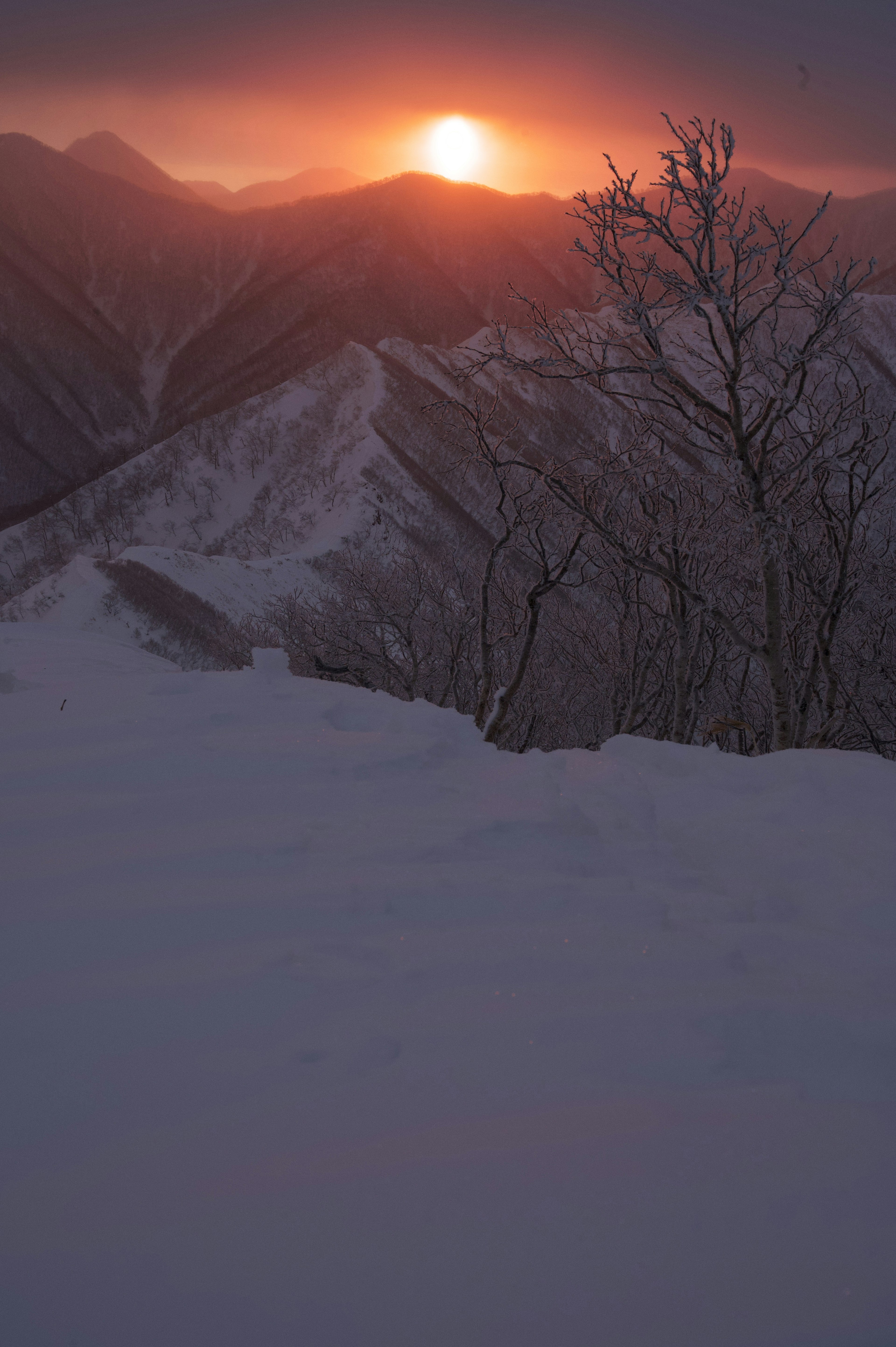 Beautiful sunset view with the sun rising between snow-covered mountains