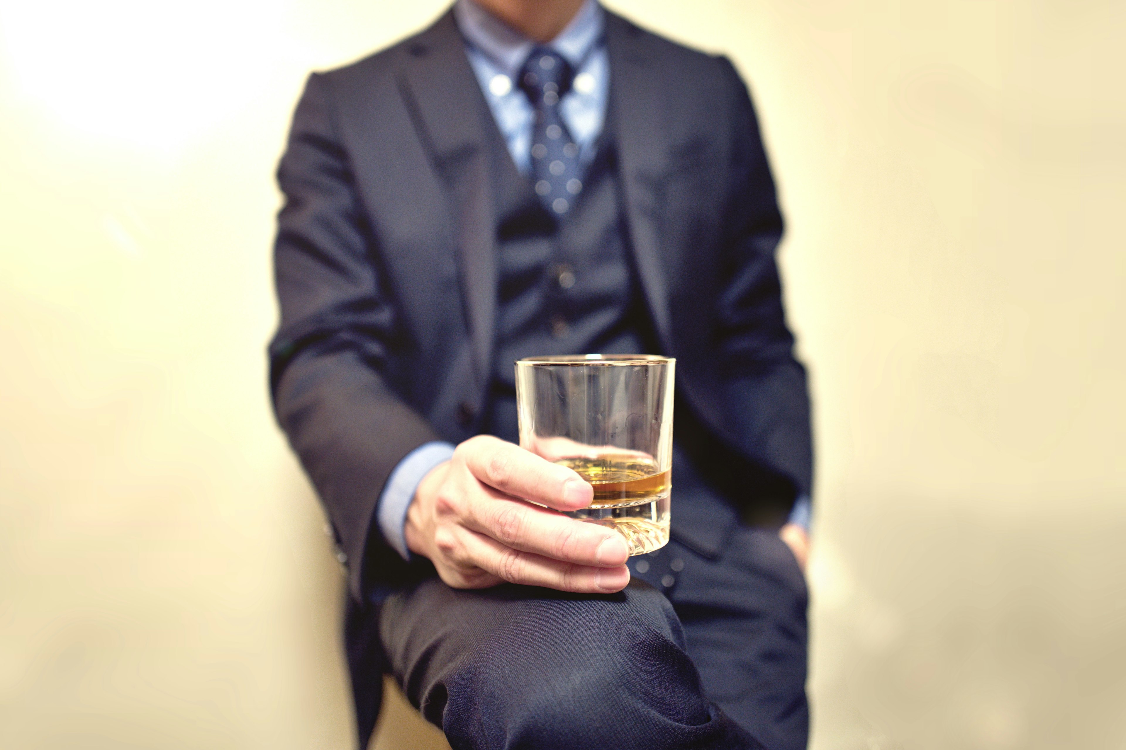 A man in a suit holding a glass of whiskey