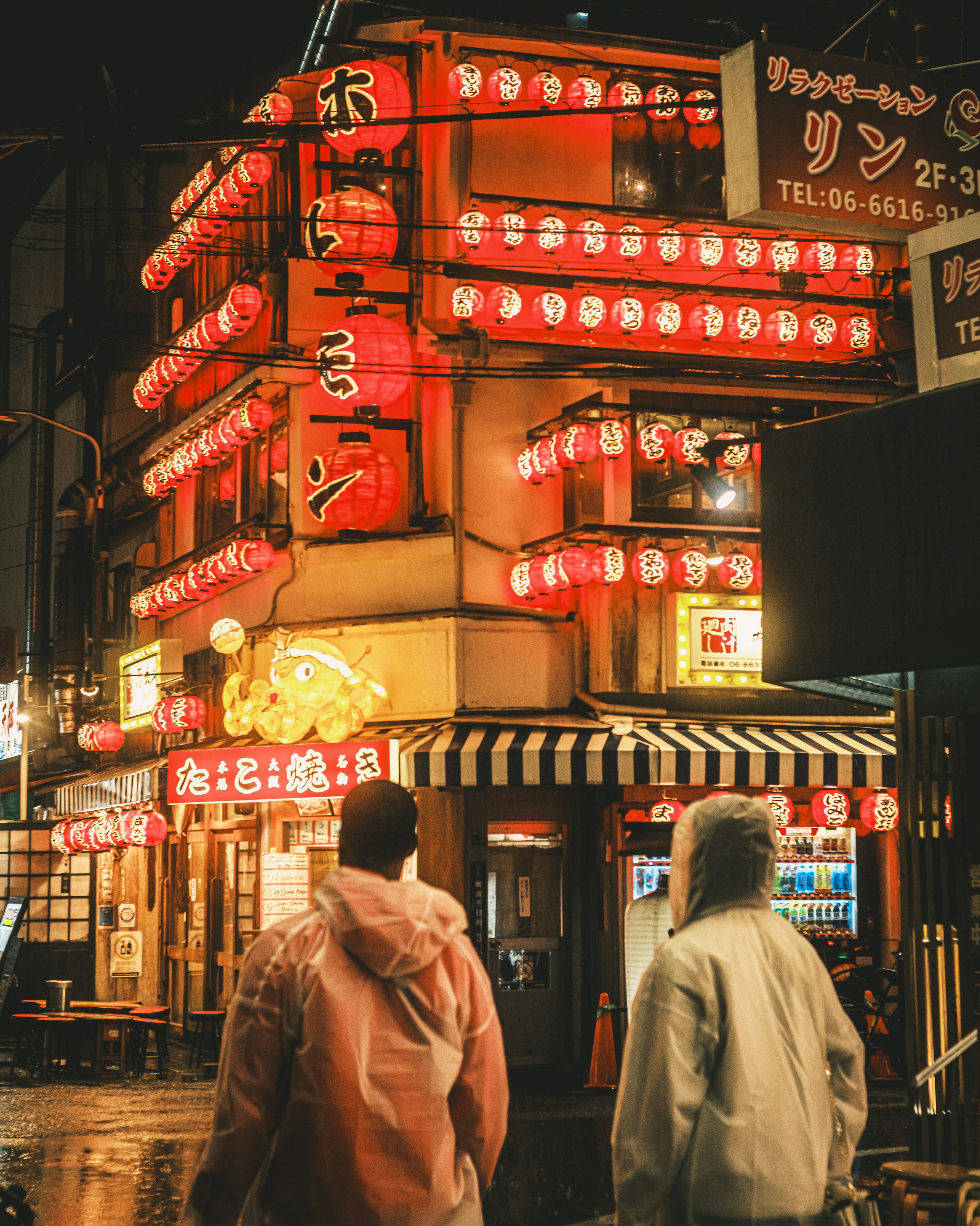 ร้านอาหารญี่ปุ่นที่มีโคมไฟแดงสว่างในฉากถนนยามค่ำคืน