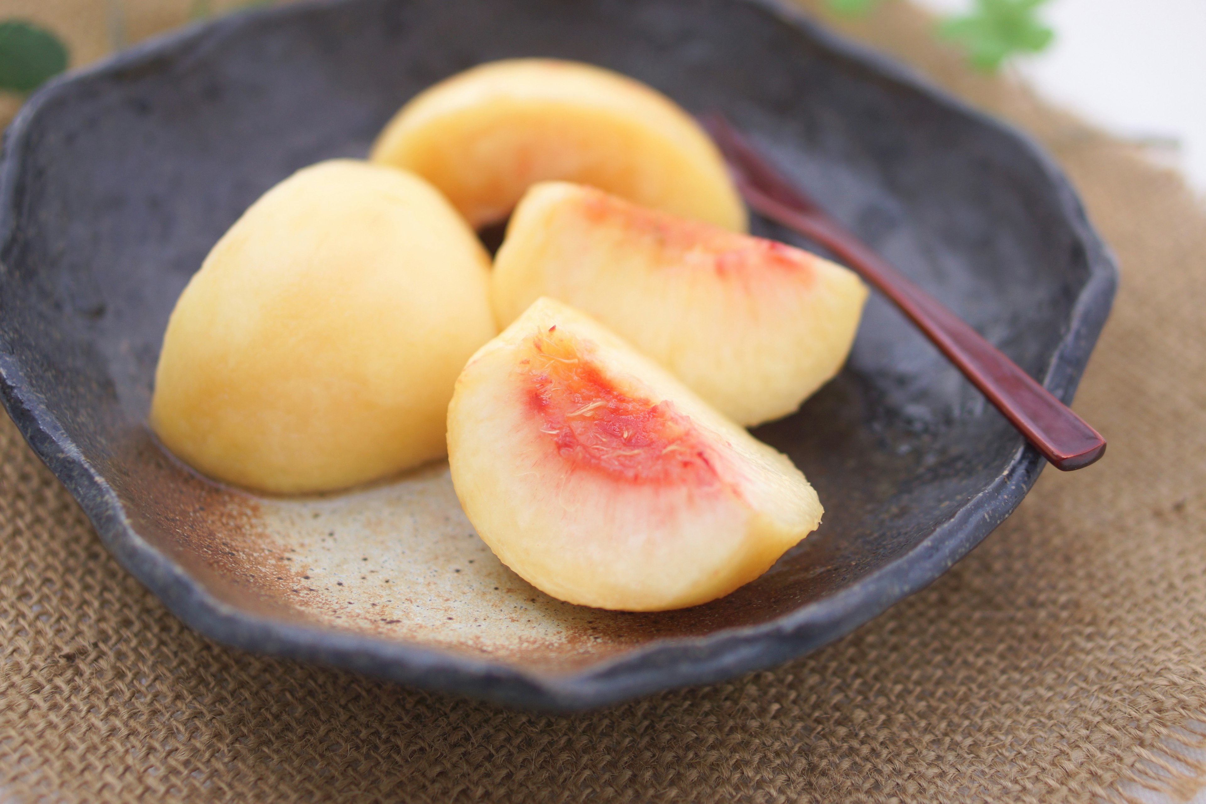 Duraznos en rodajas en un plato oscuro con una cuchara