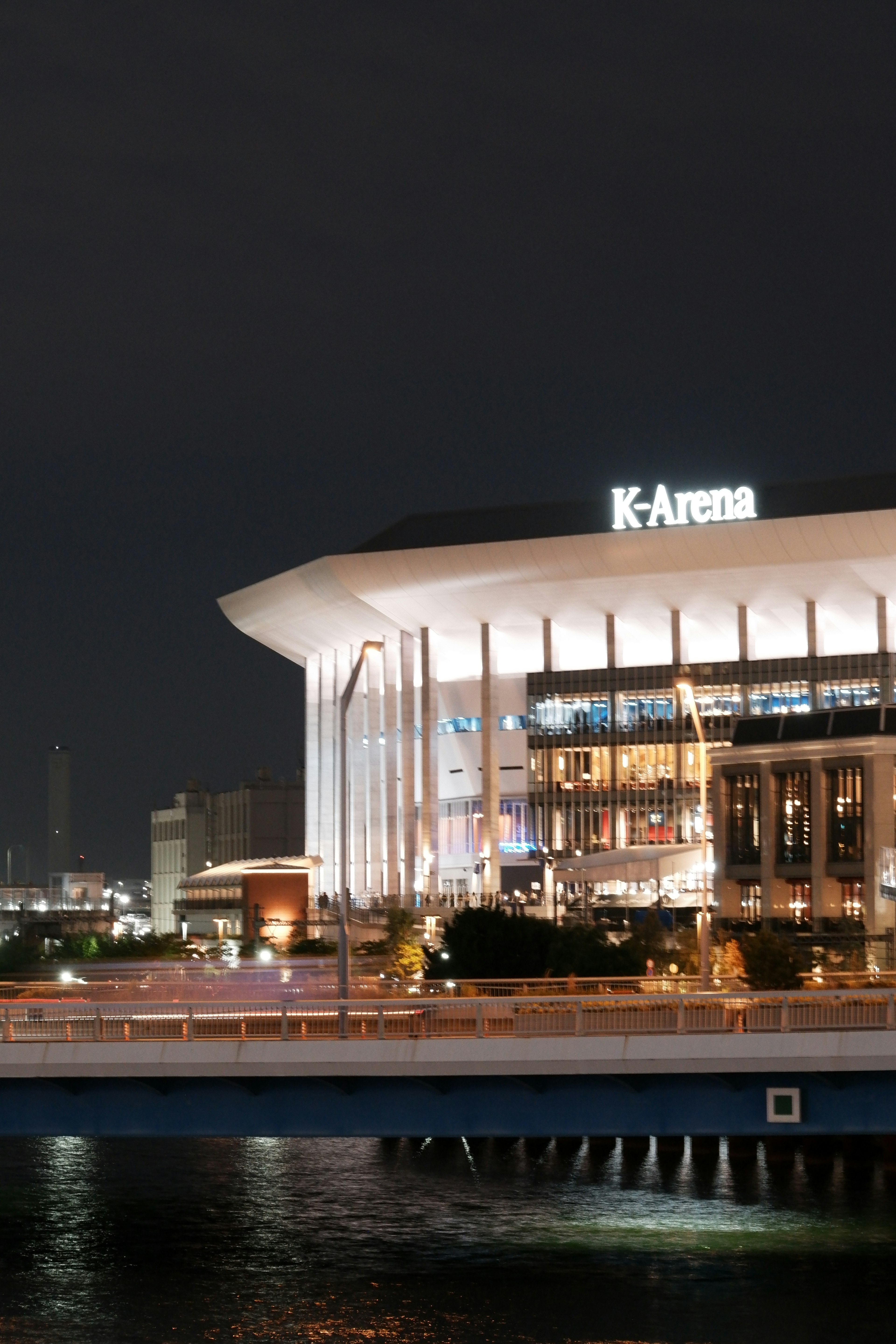 Vue nocturne du K-Arena mettant en valeur son architecture unique et la zone environnante