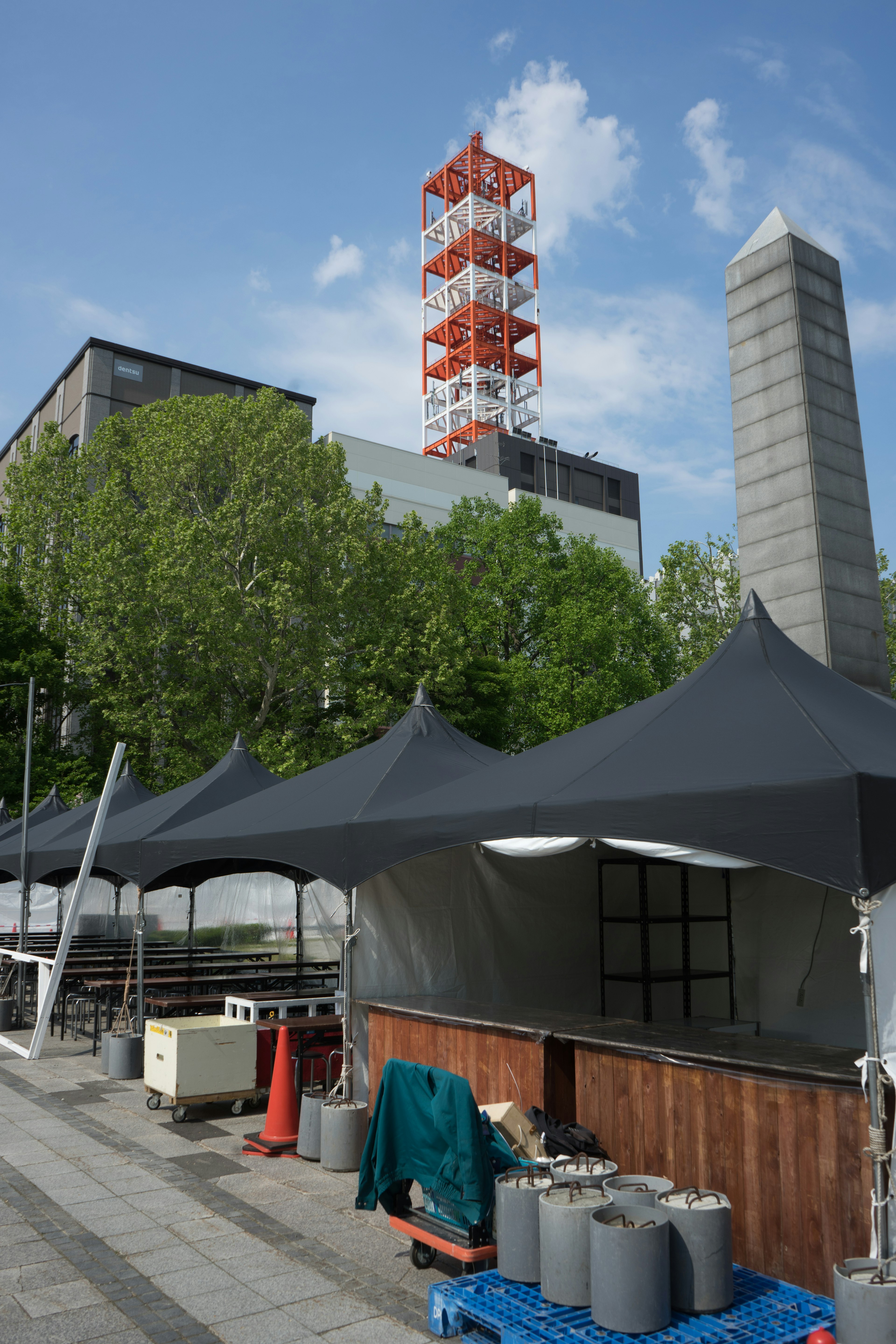 屋外の黒いテントと緑の木々の景色 高い赤い煙突が目立つ