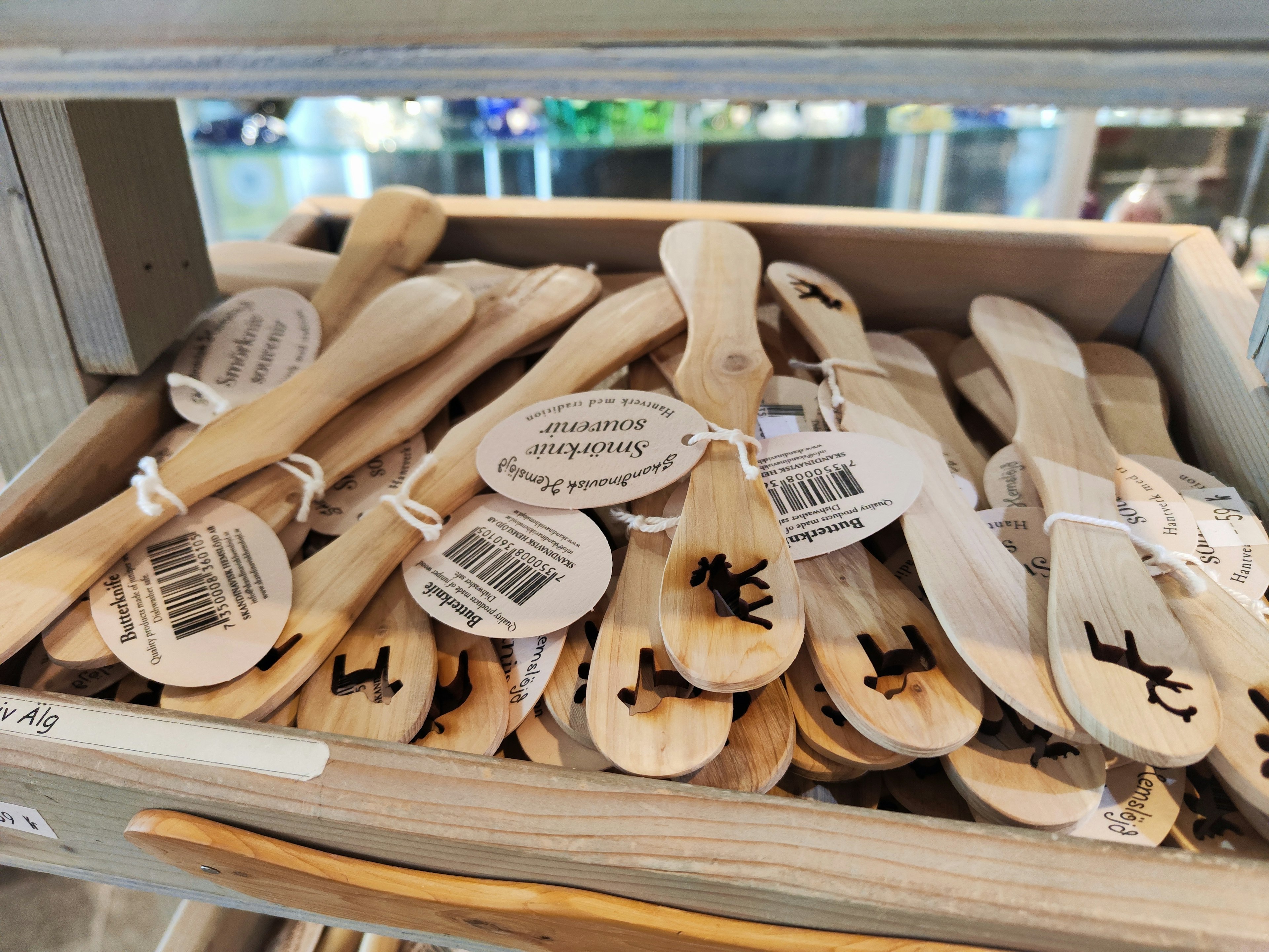 A box filled with wooden spoons featuring tags and designs