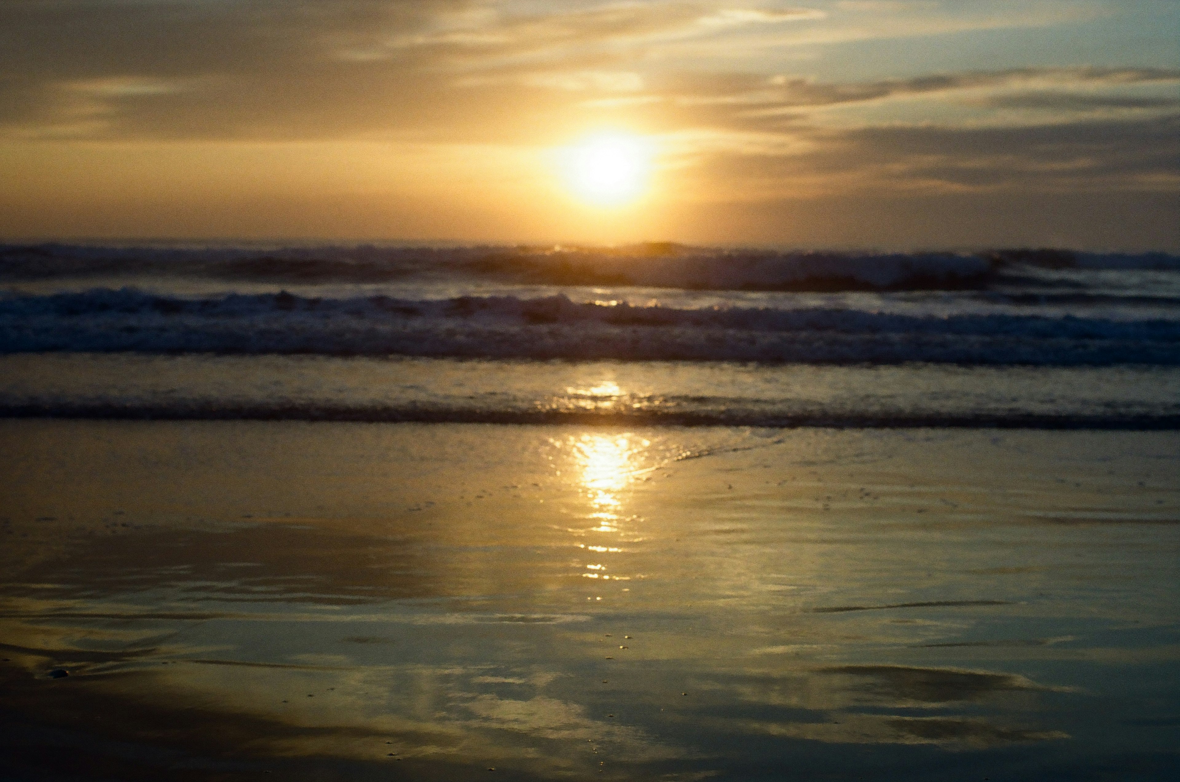 Una escena de playa tranquila con el atardecer reflejándose en el agua