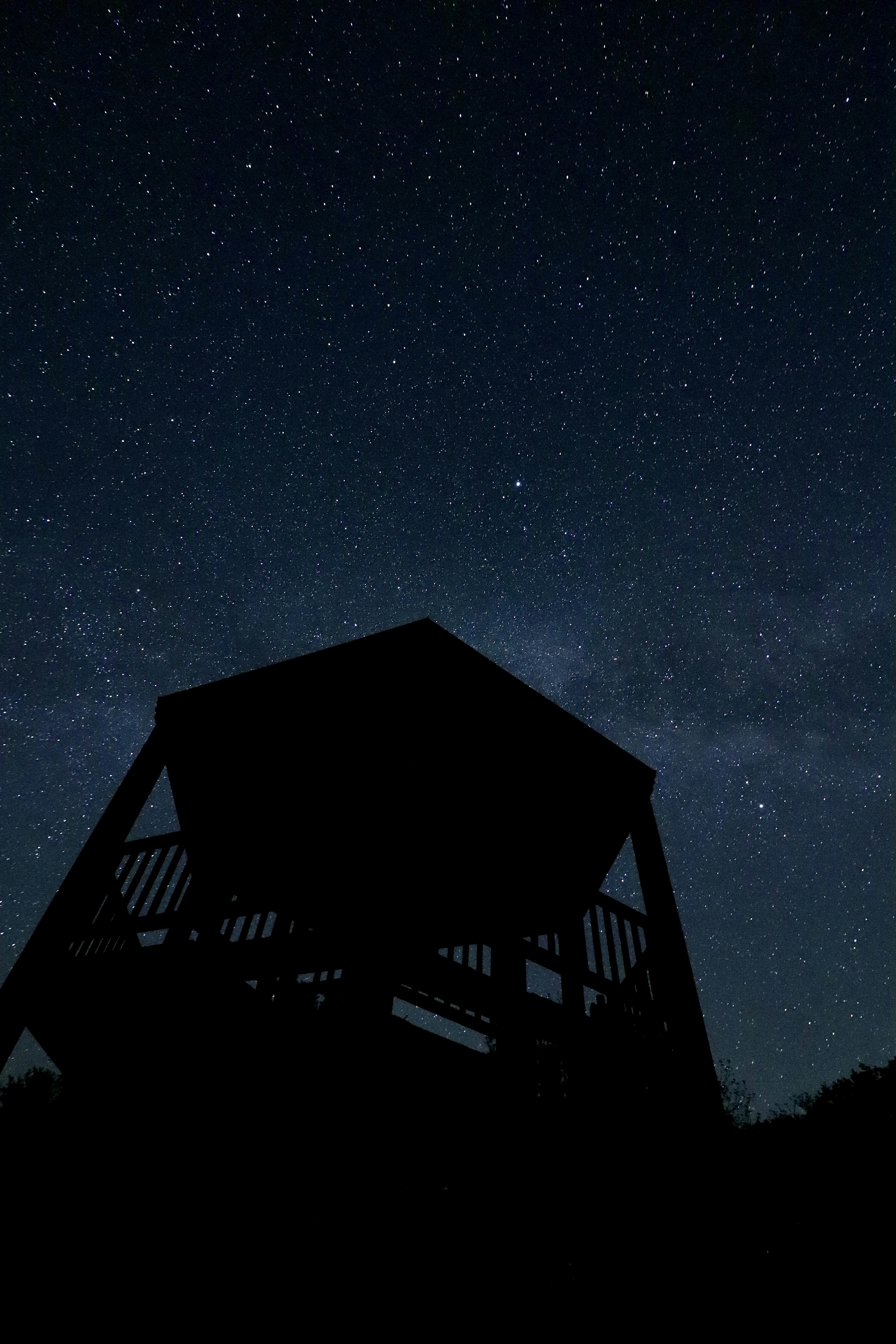 Silhouetted observation hut under a starry sky