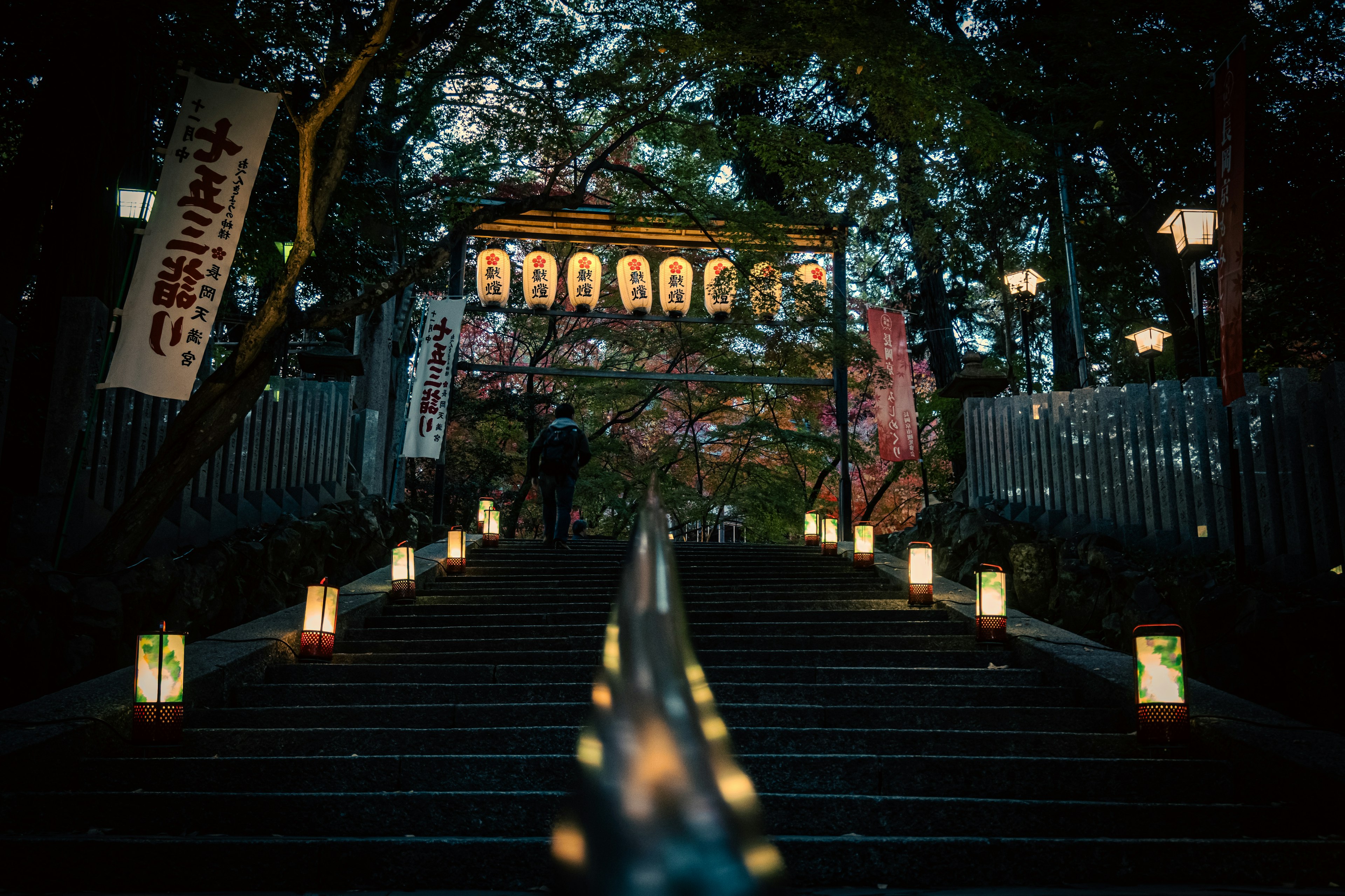 Staircase lined with lanterns leading to a building under the night sky