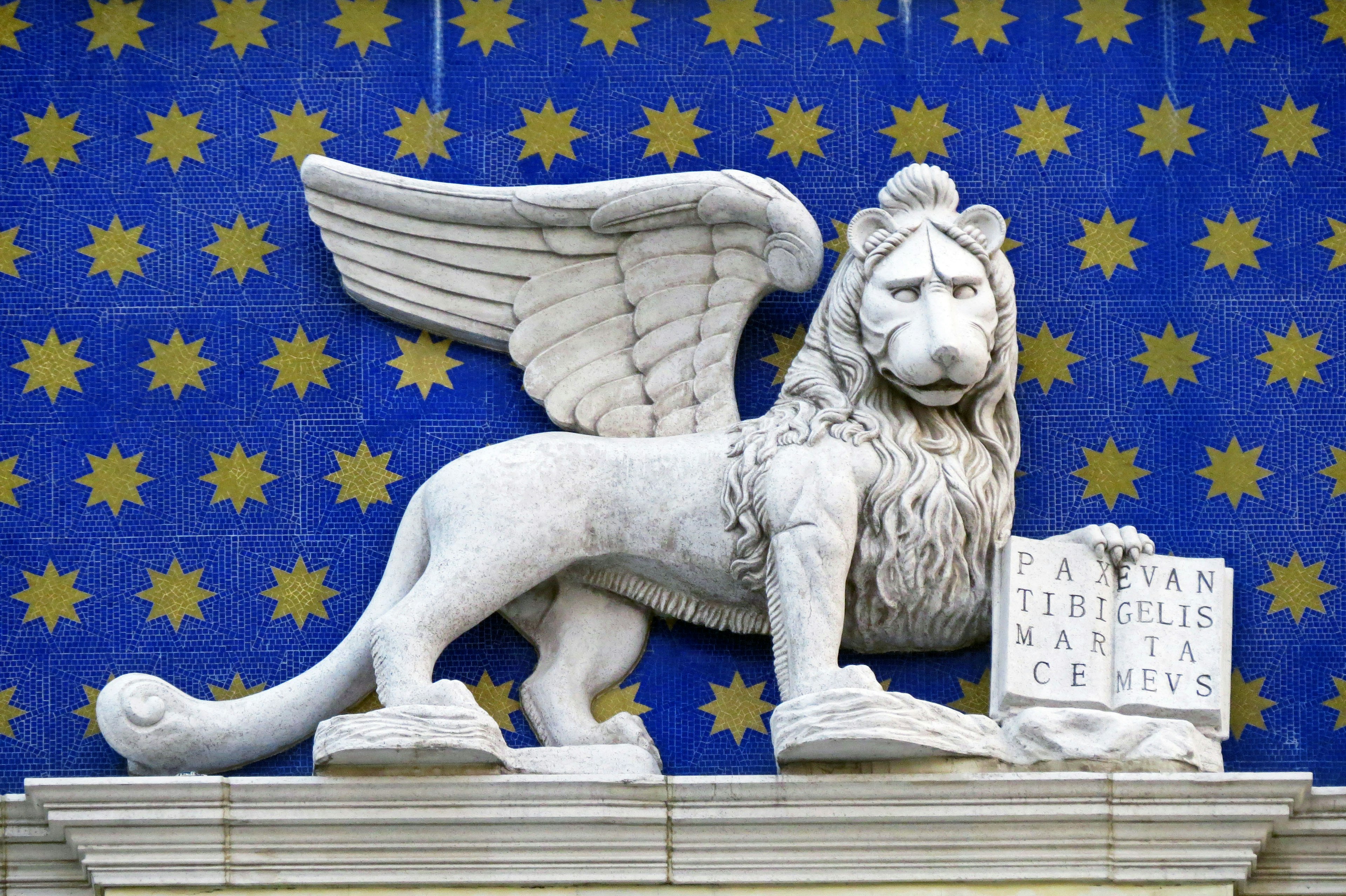 Escultura de león alado sobre un fondo azul con estrellas doradas