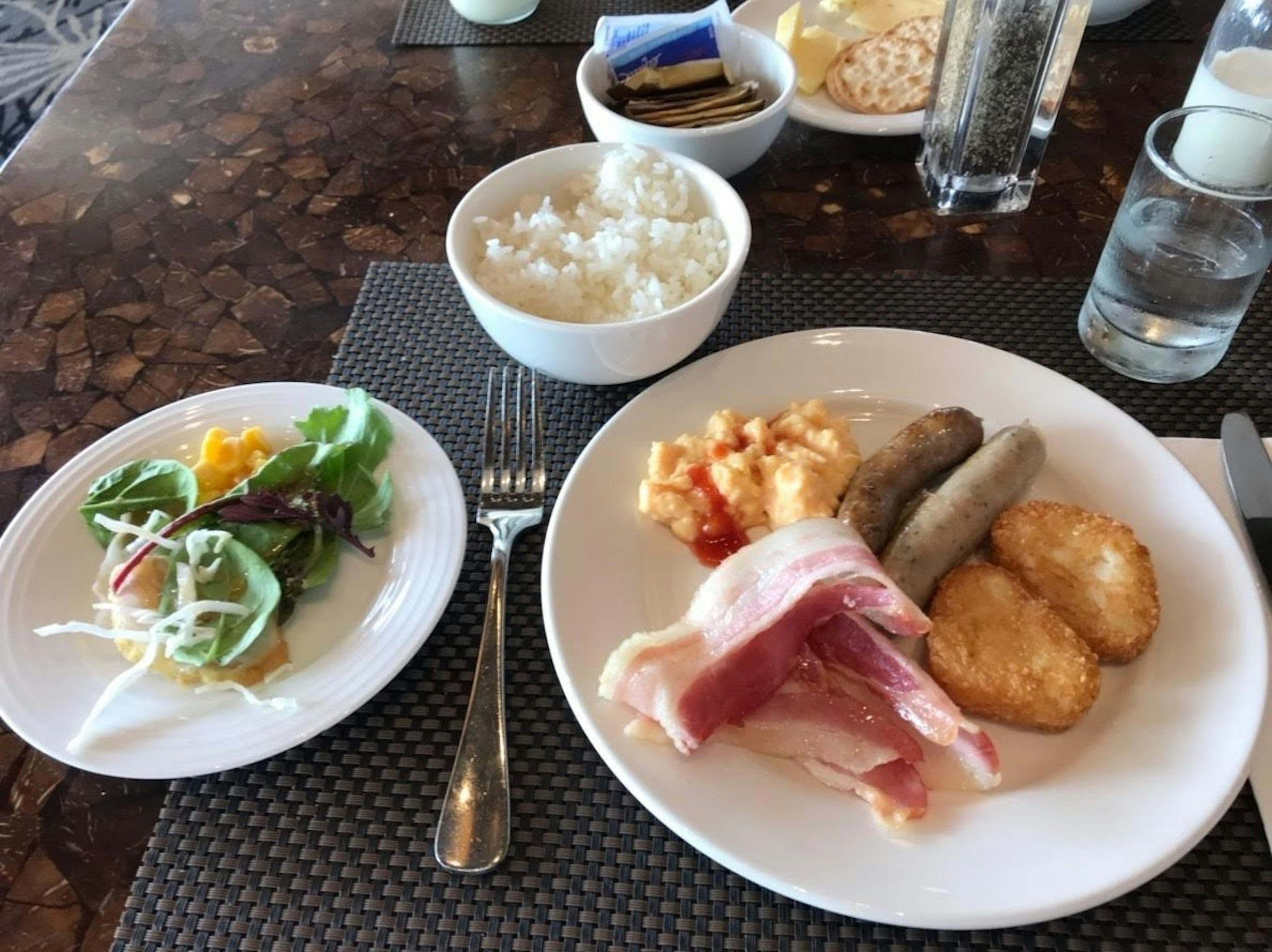 Breakfast plate featuring a variety of dishes salad rice ham sausage