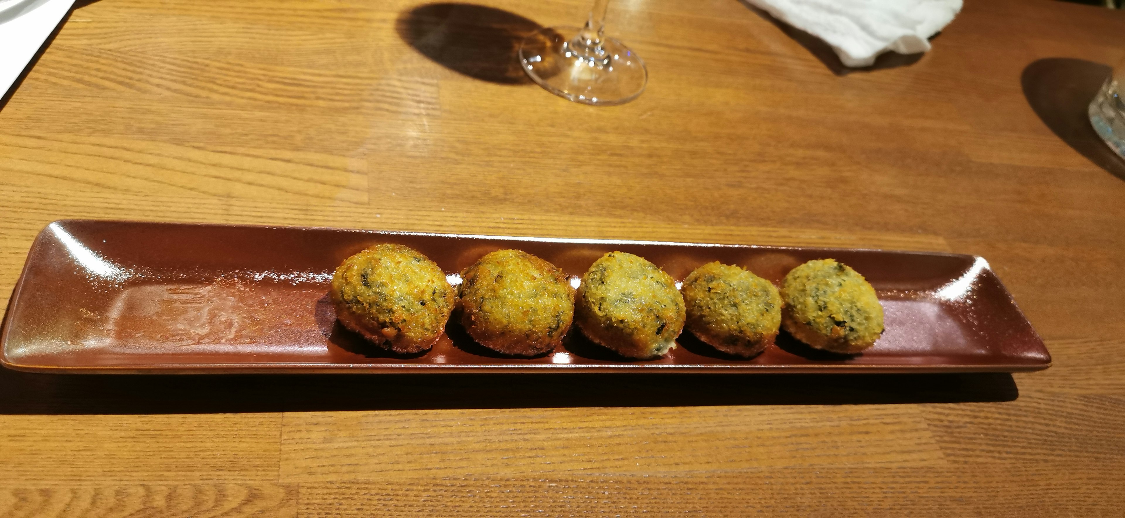 Four fried balls arranged on a rectangular plate