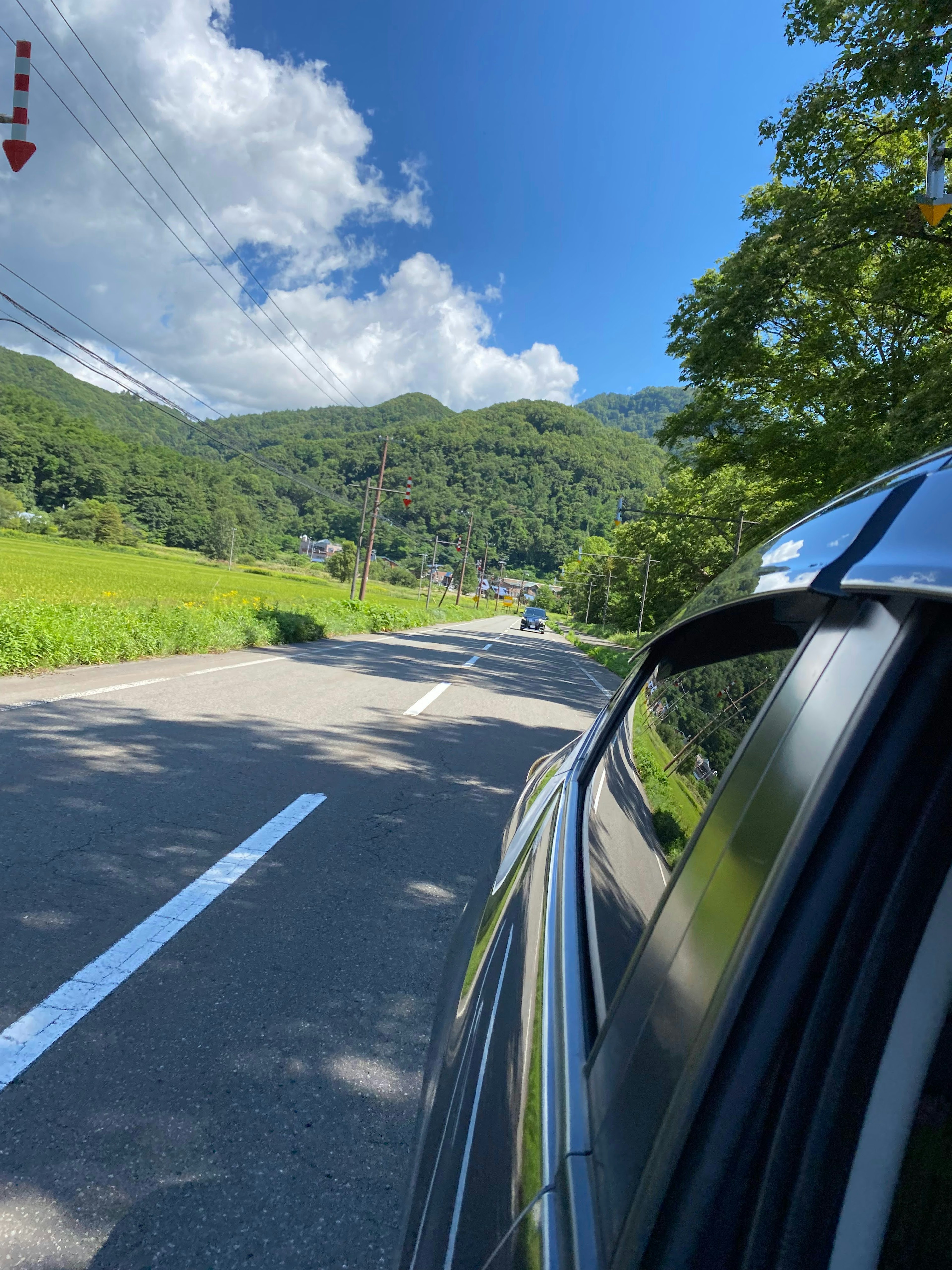 Vista escénica de montañas verdes y cielo azul desde una ventana de coche en una carretera rural