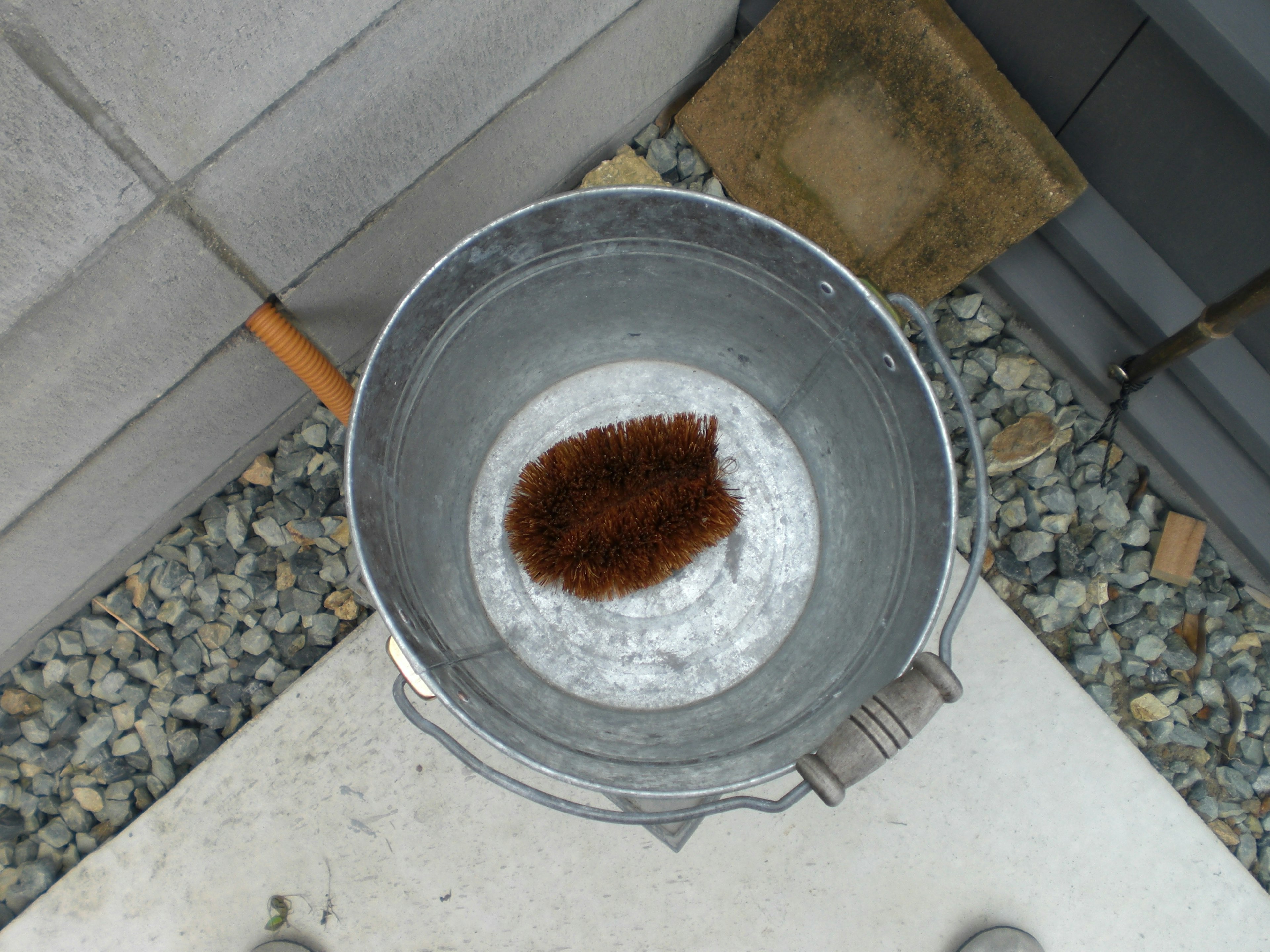 A silver bucket containing a brown object with small stones surrounding it