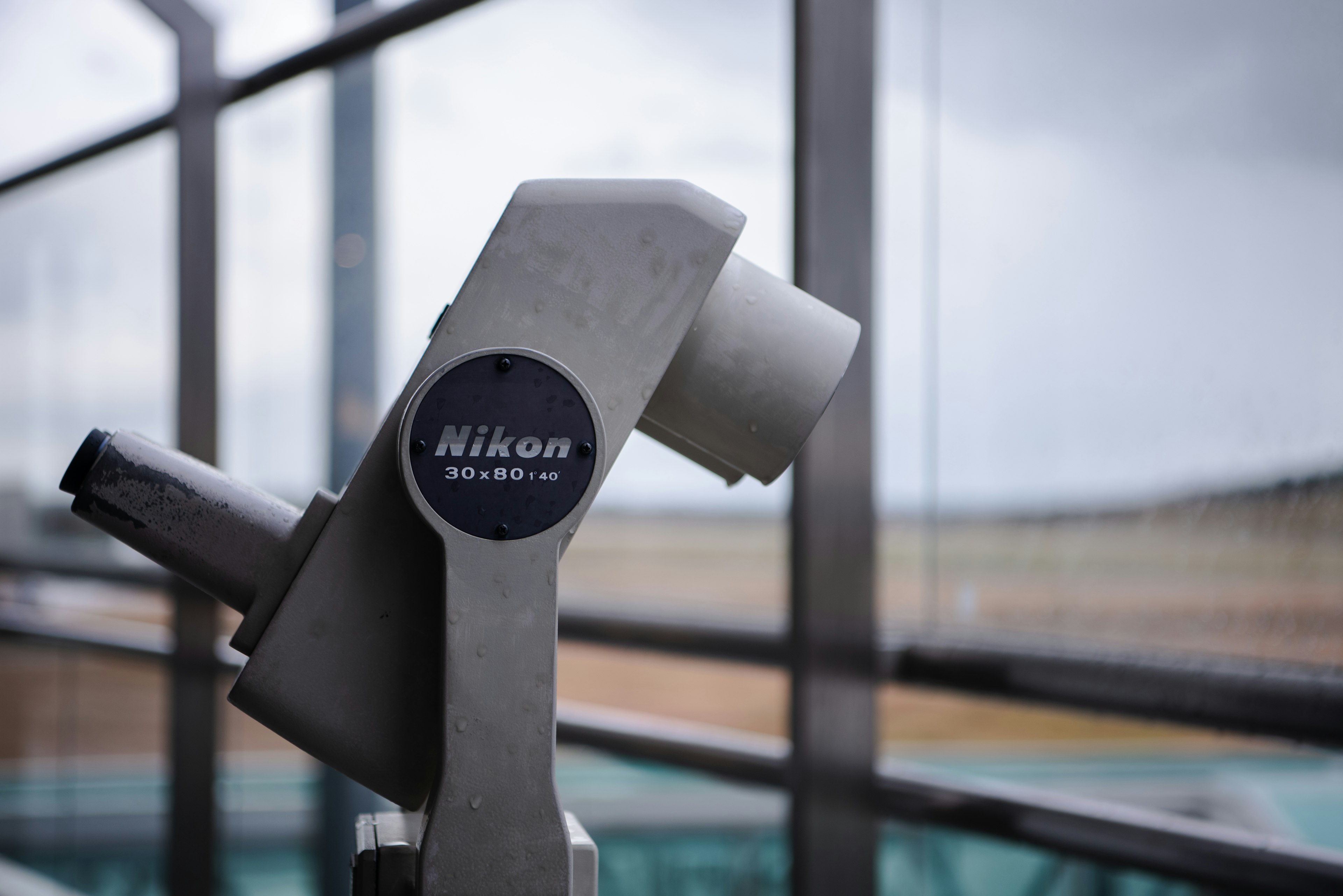 Nikon-Teleskop nahe einem Fenster mit bewölktem Himmel im Hintergrund