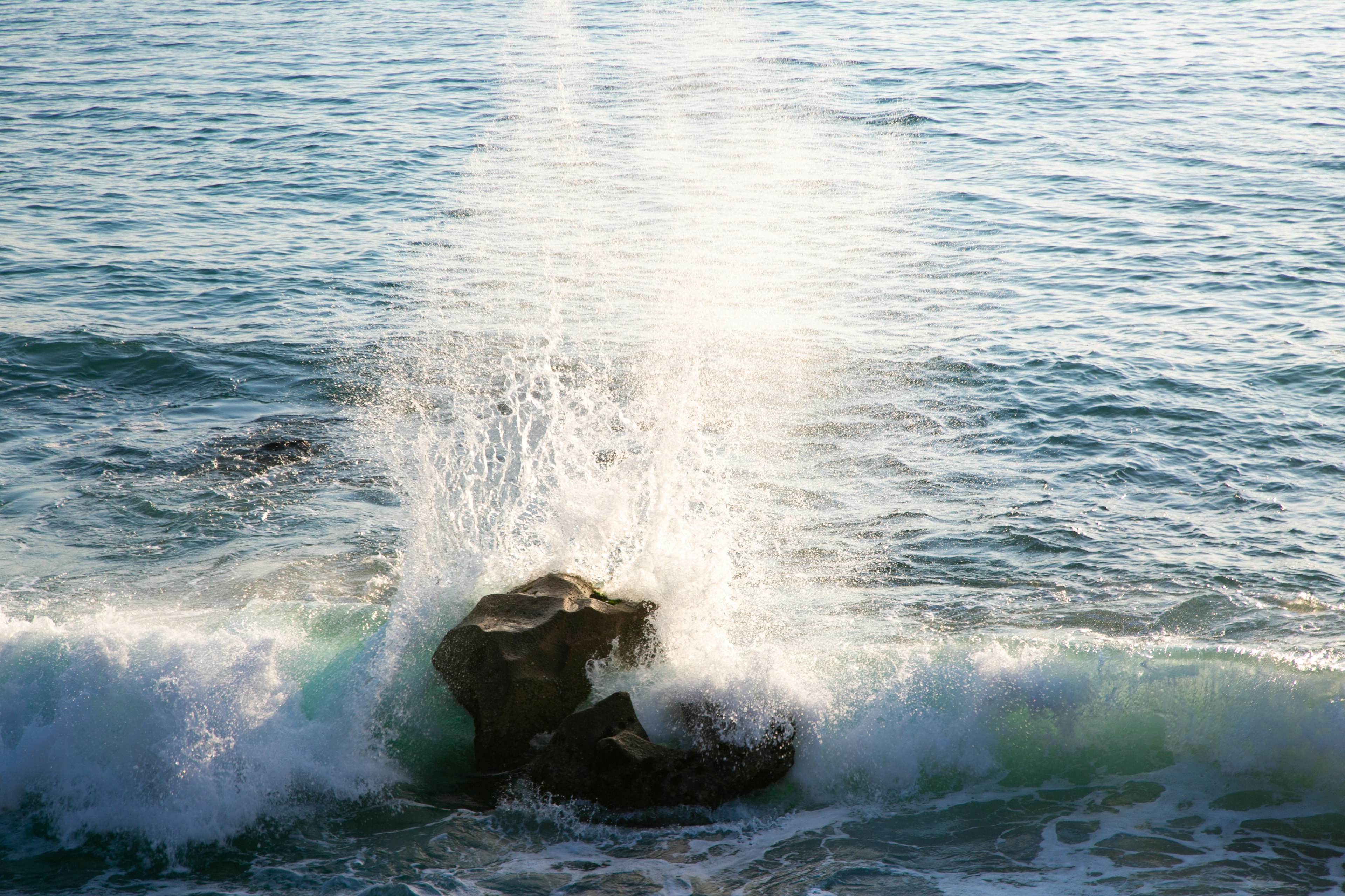 Waves crashing against a rock creating a spray of water