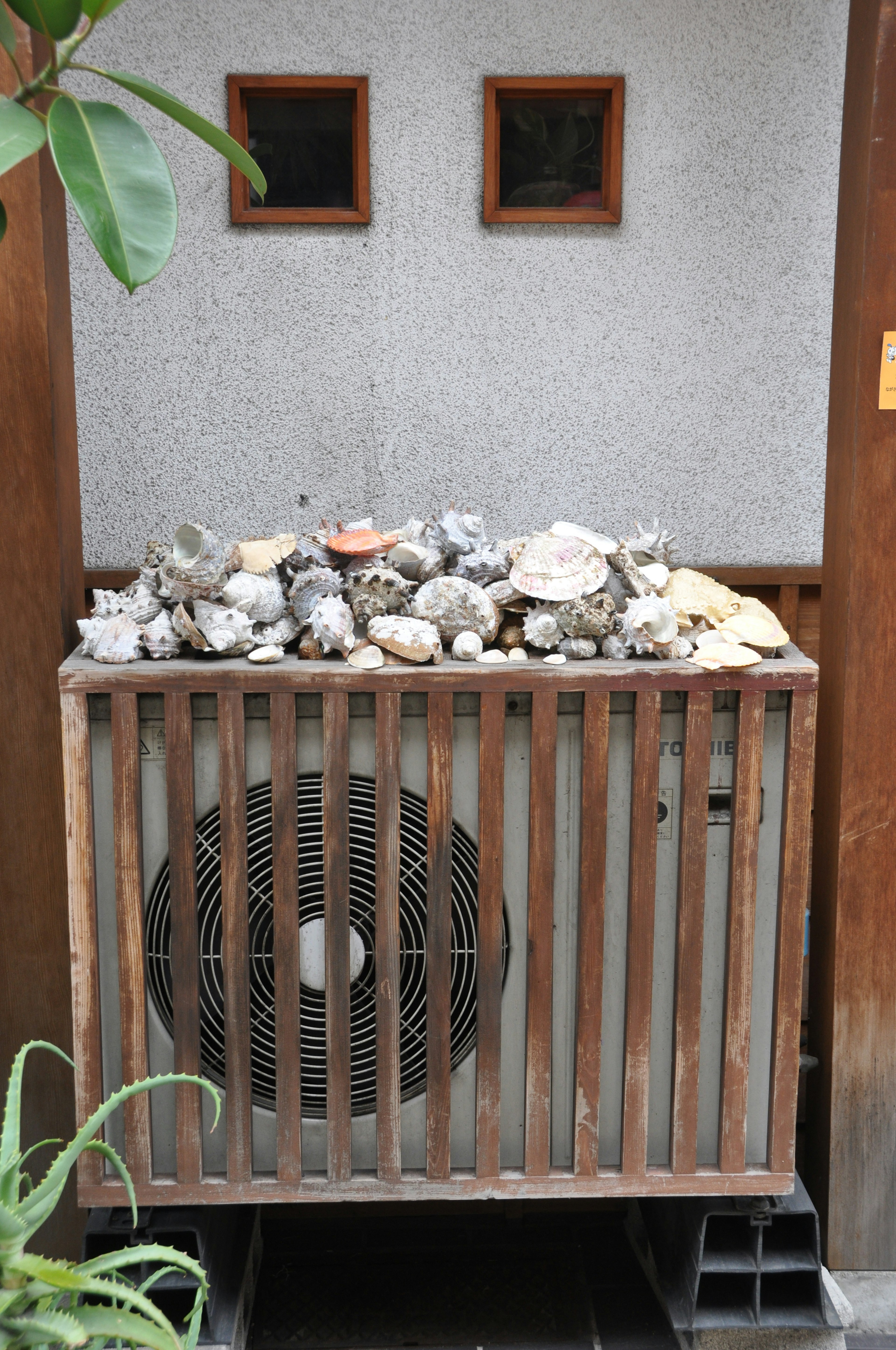 Air conditioning unit enclosed with wooden slats topped with stones