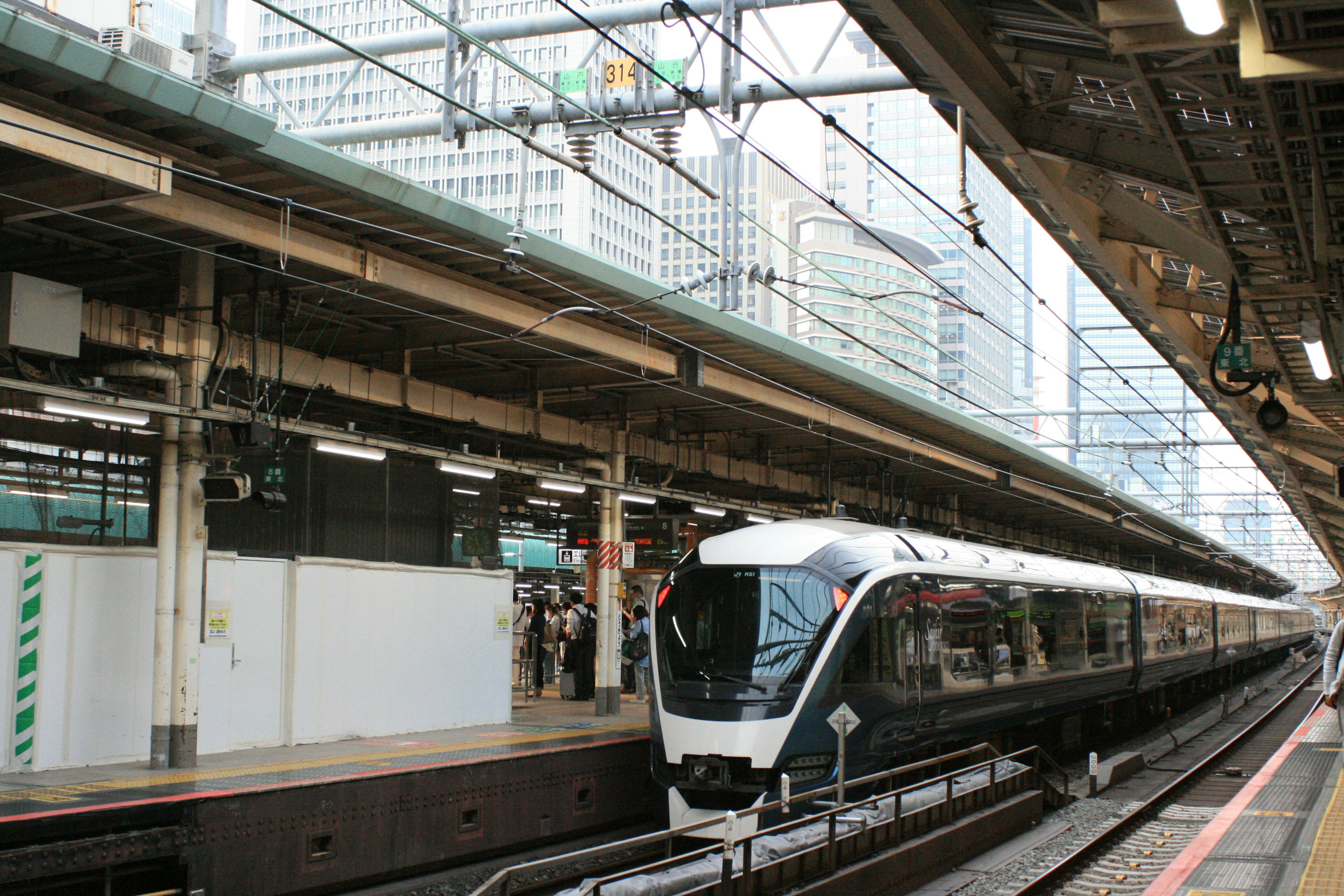 A modern train is parked at a station with a bustling atmosphere