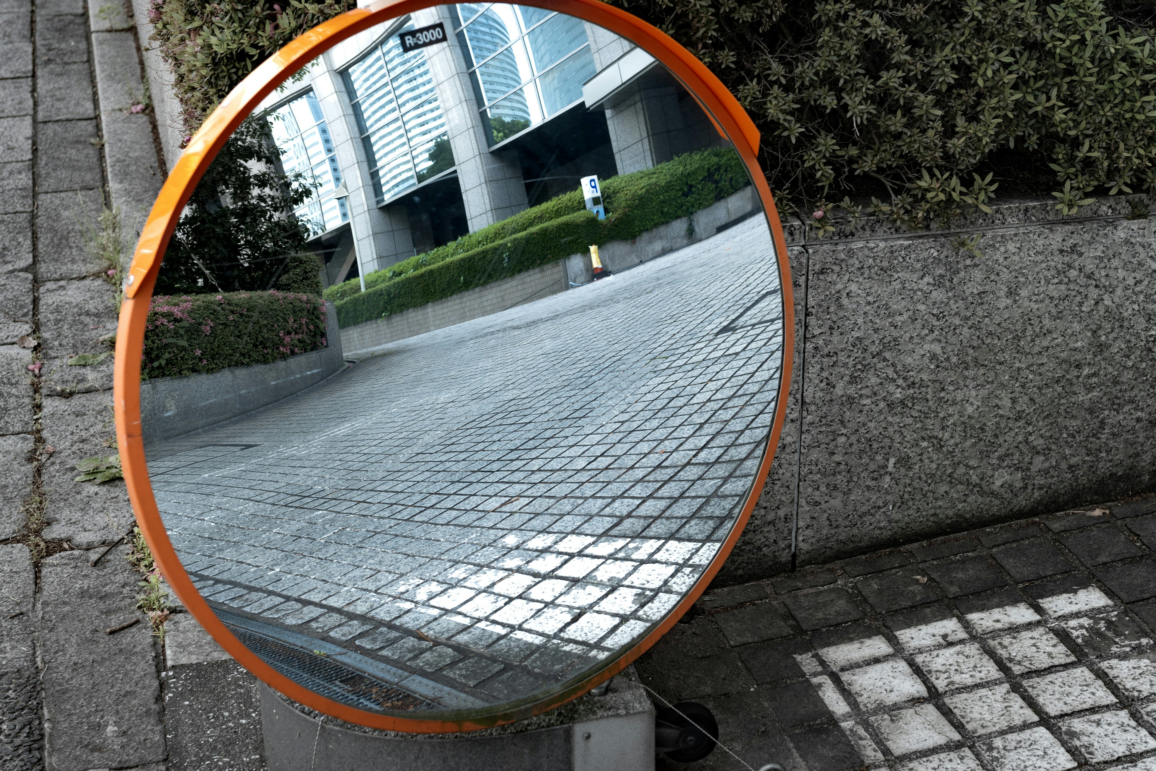 Orange-framed convex mirror reflecting urban scenery