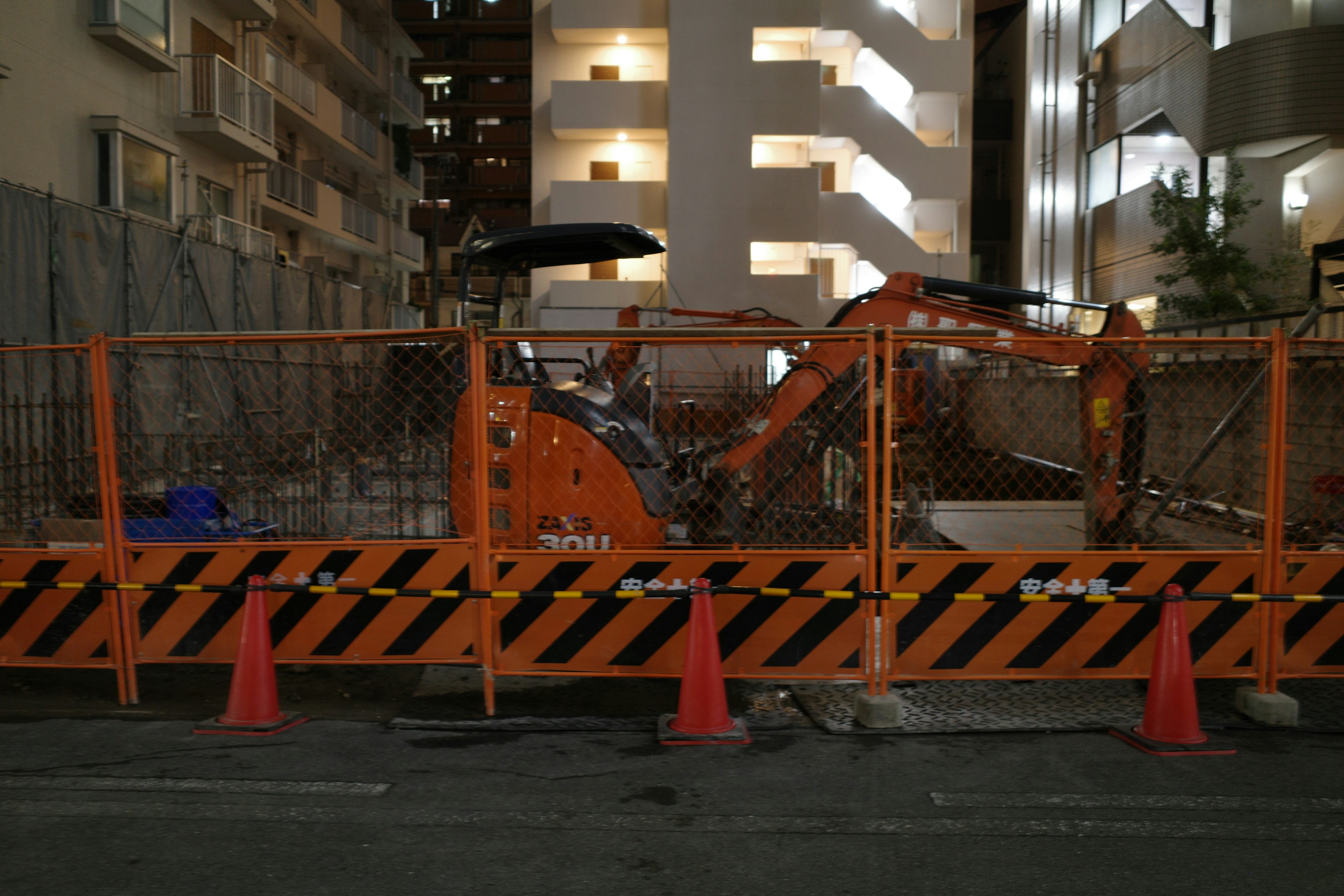 夜の工事現場のオレンジ色の重機とバリケード