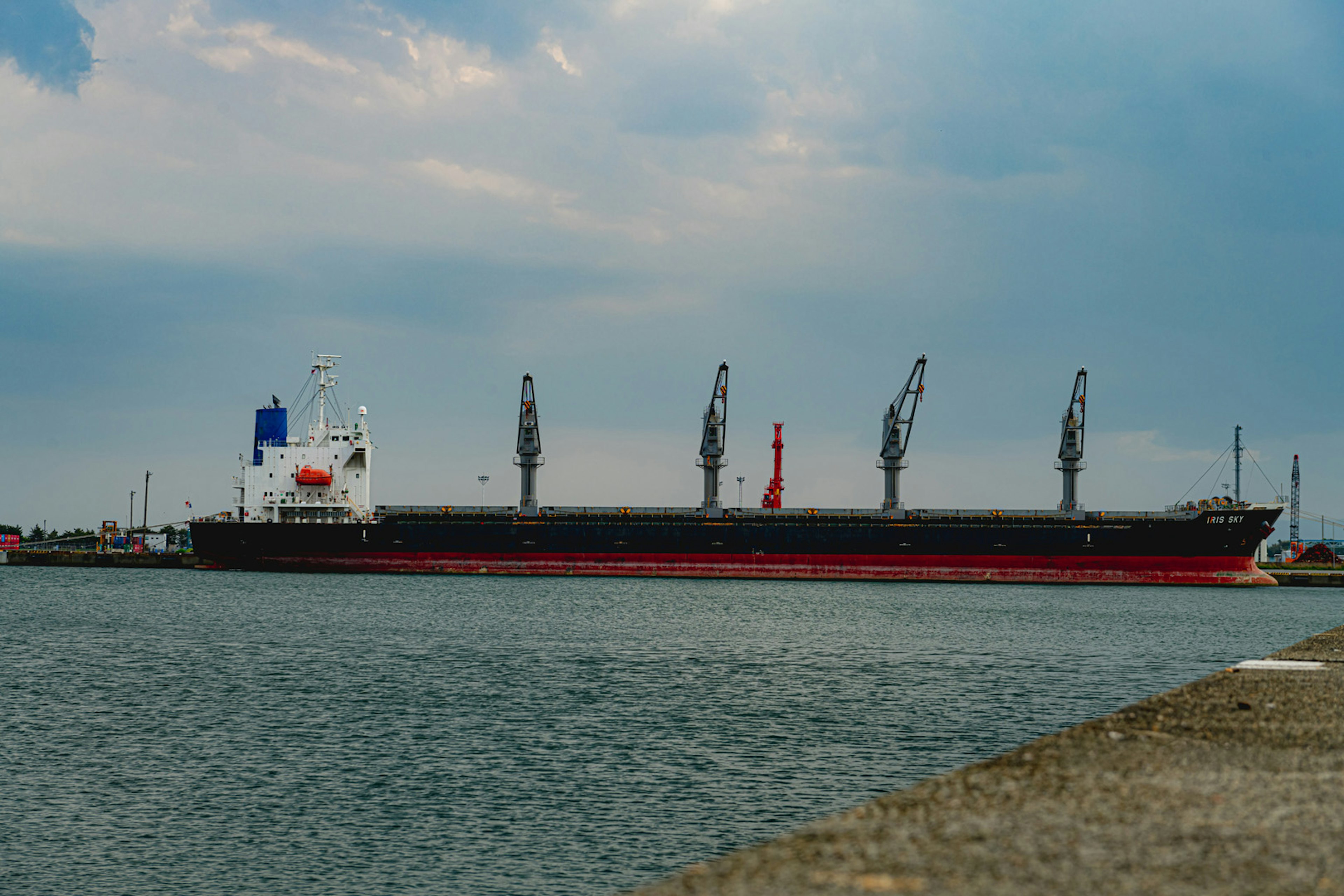 Large cargo ship docked at the port with cranes in the background