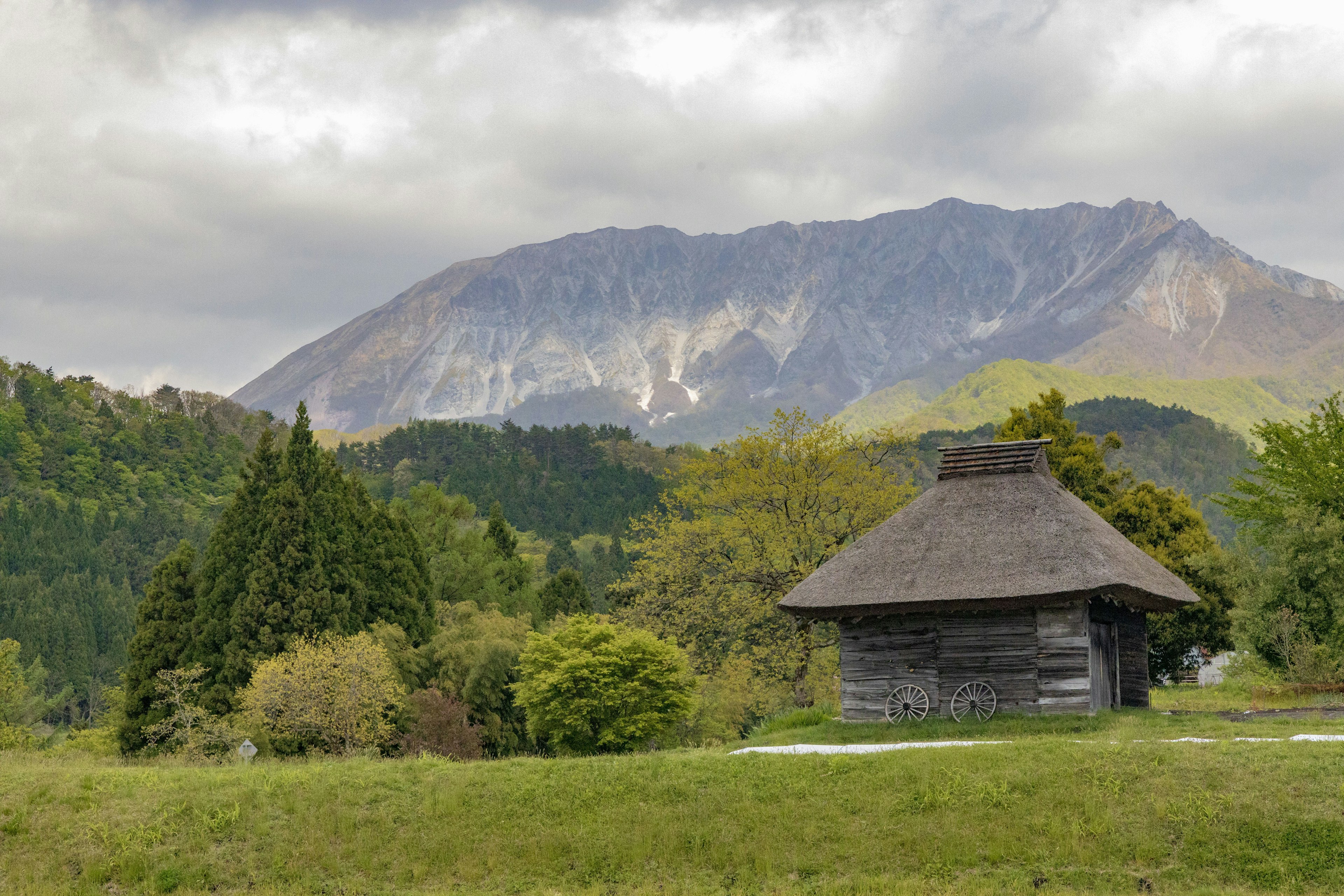 Traditional wooden cabin surrounded by mountains and greenery