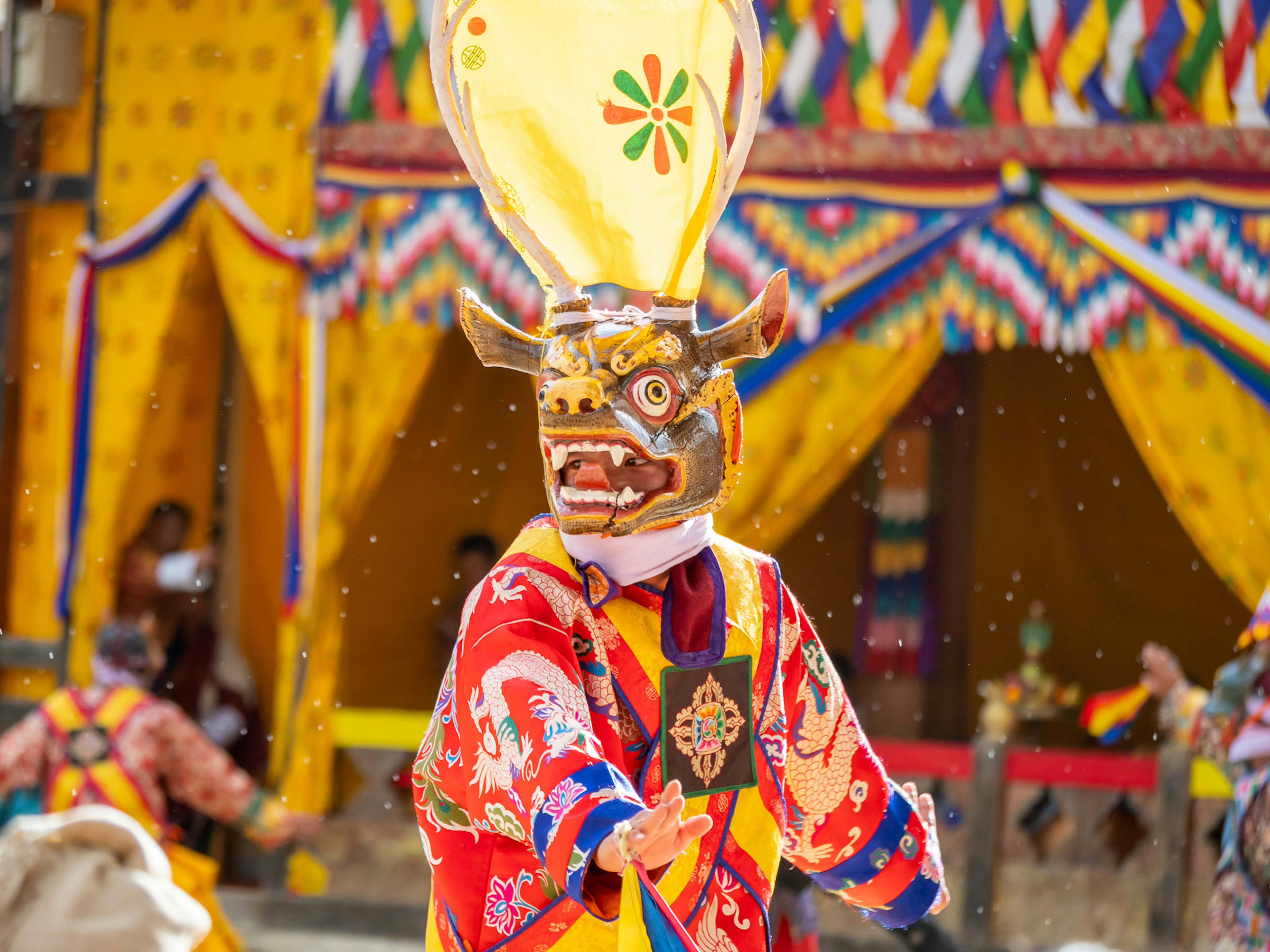 Una persona con vestimenta colorida usando una máscara tradicional mientras baila