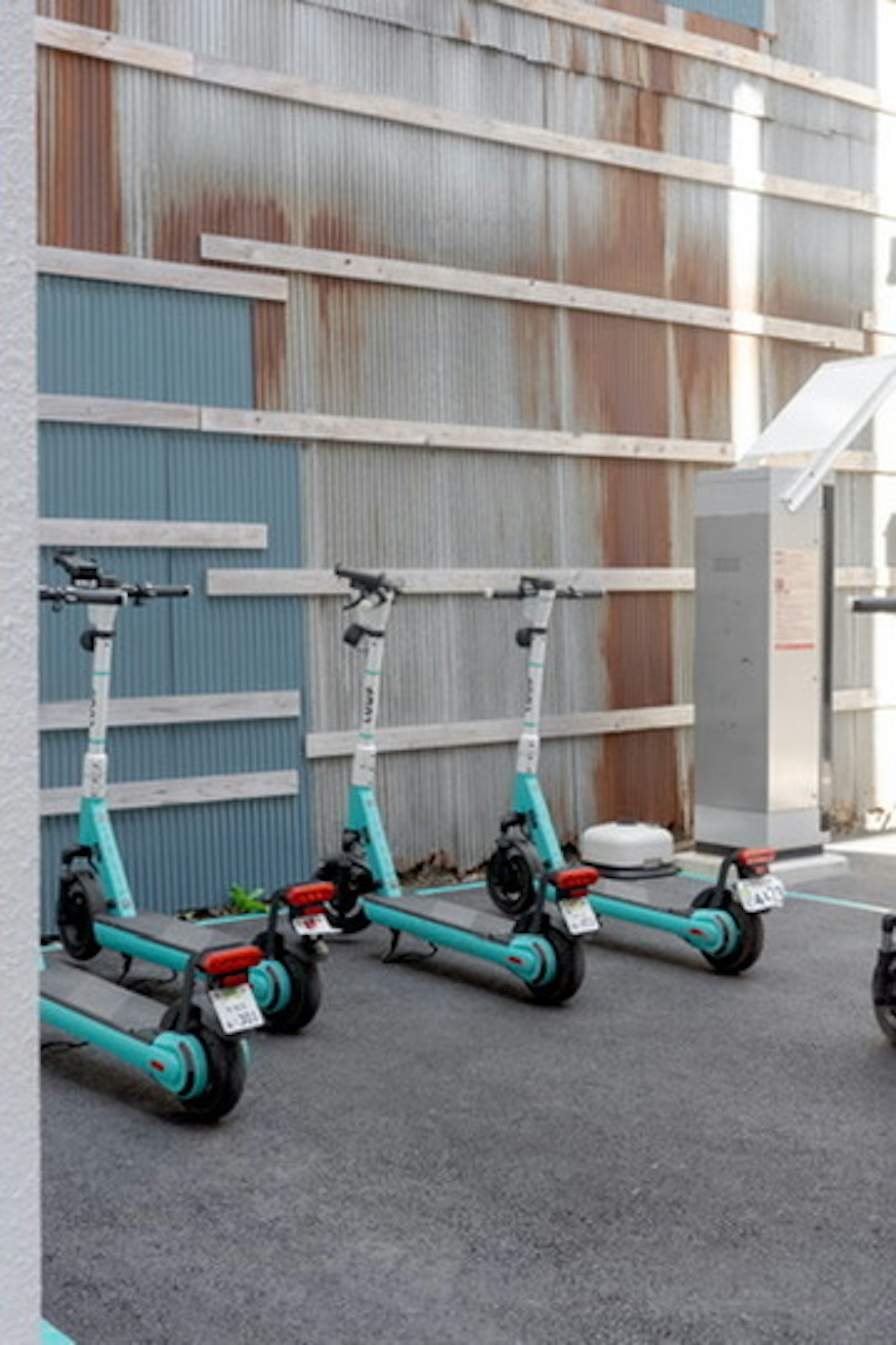 Row of blue electric scooters parked against a textured wall