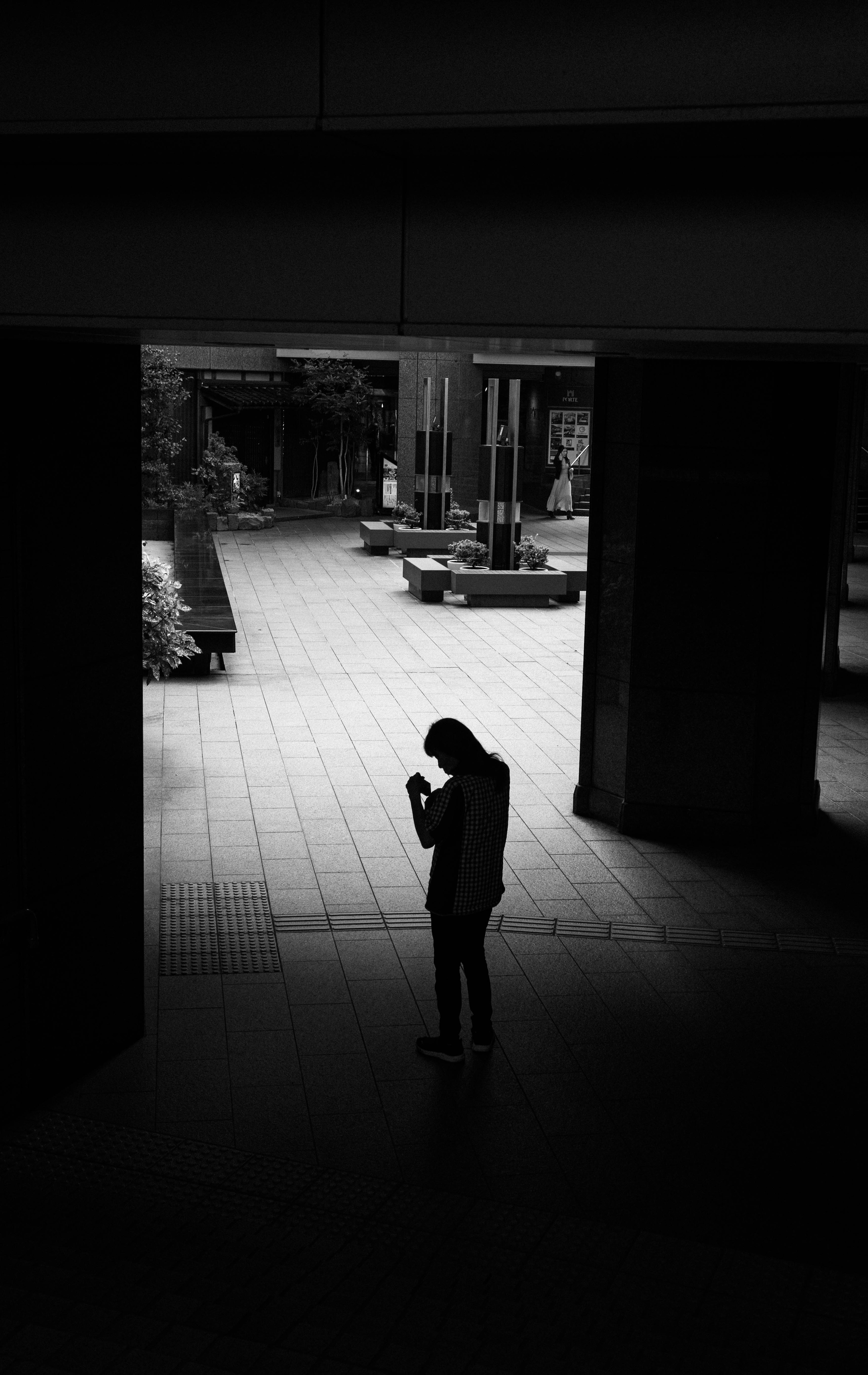 Silhouette di una persona che usa uno smartphone in un contesto urbano