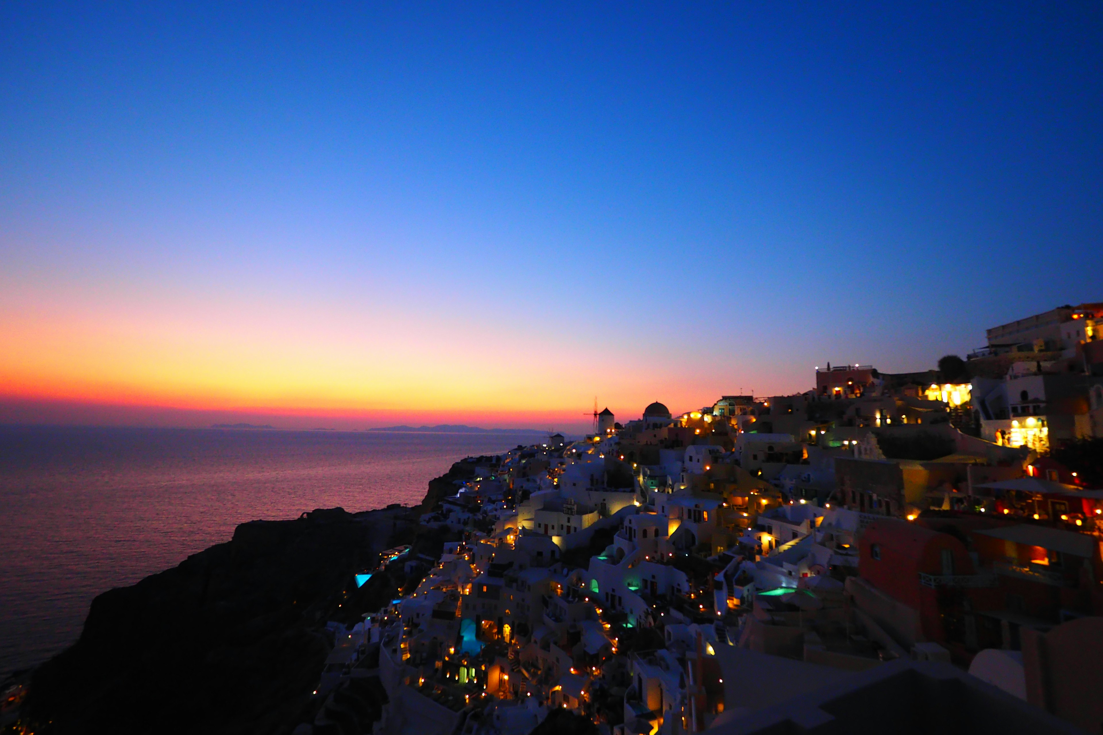 Bellissimo paesaggio di Santorini illuminato dal tramonto con silhouette di edifici bianchi