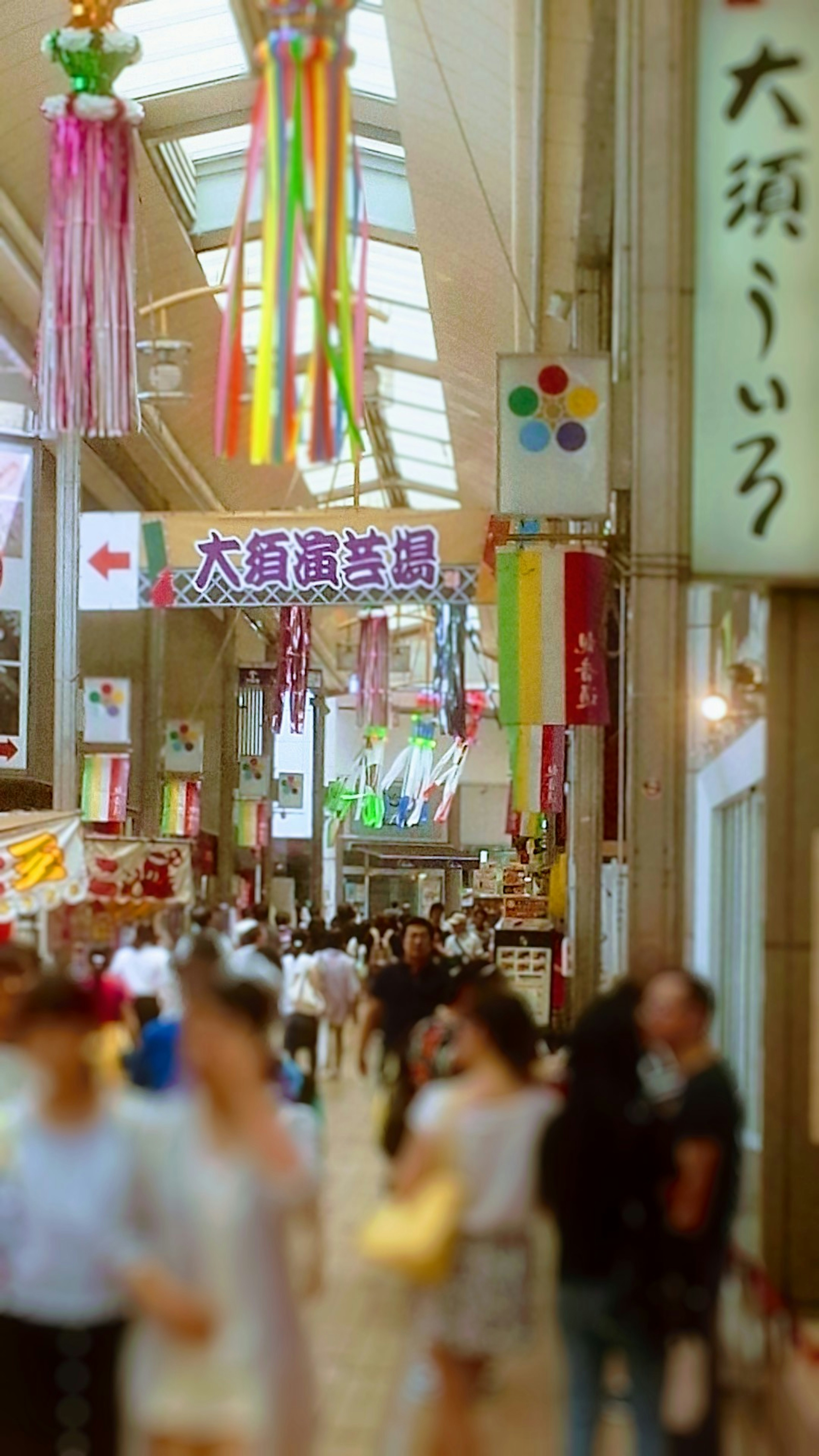 Escena de una calle comercial bulliciosa con decoraciones coloridas y gente caminando