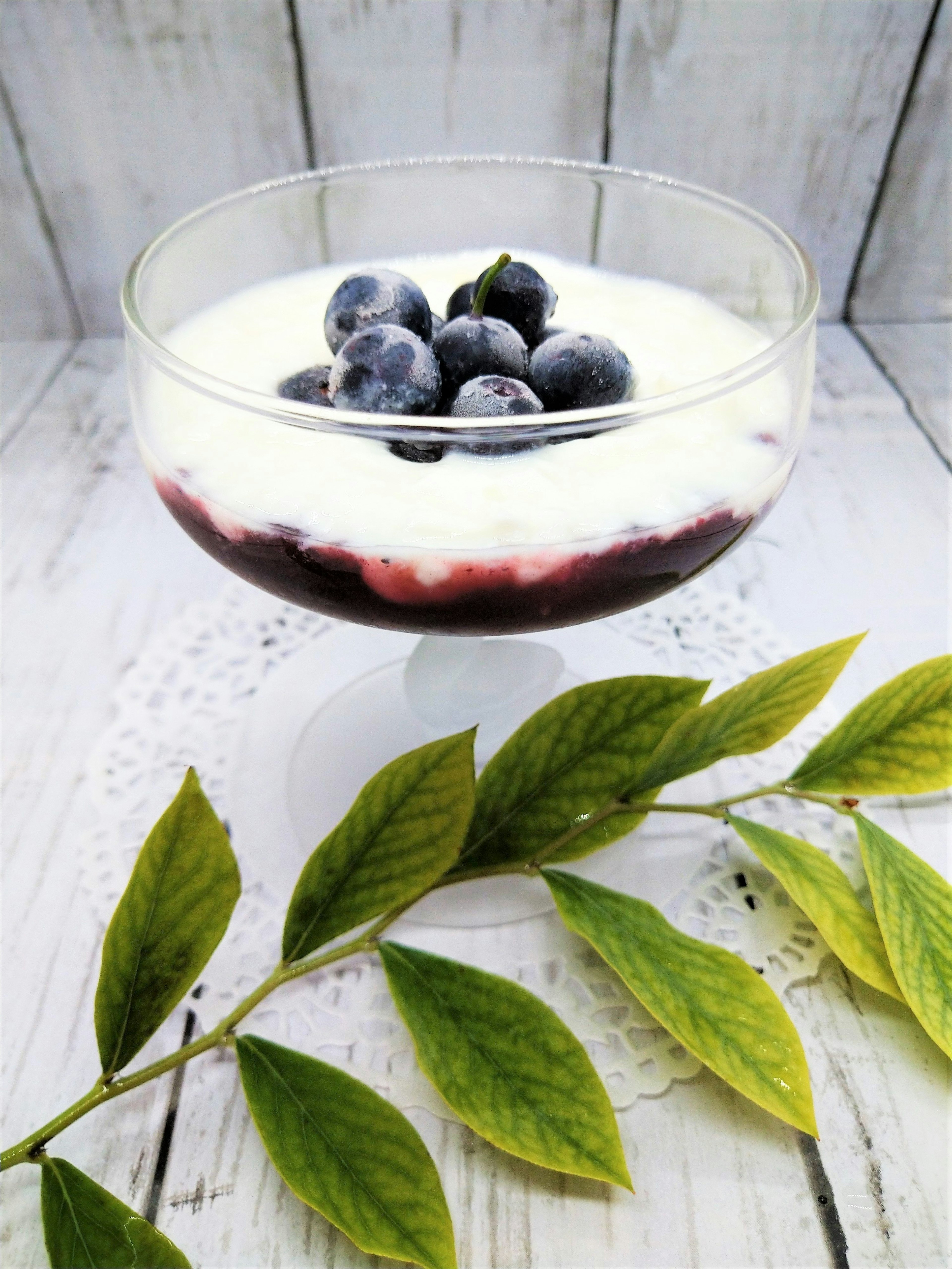 Mangkuk dessert kaca dengan blueberry dan krim di atasnya