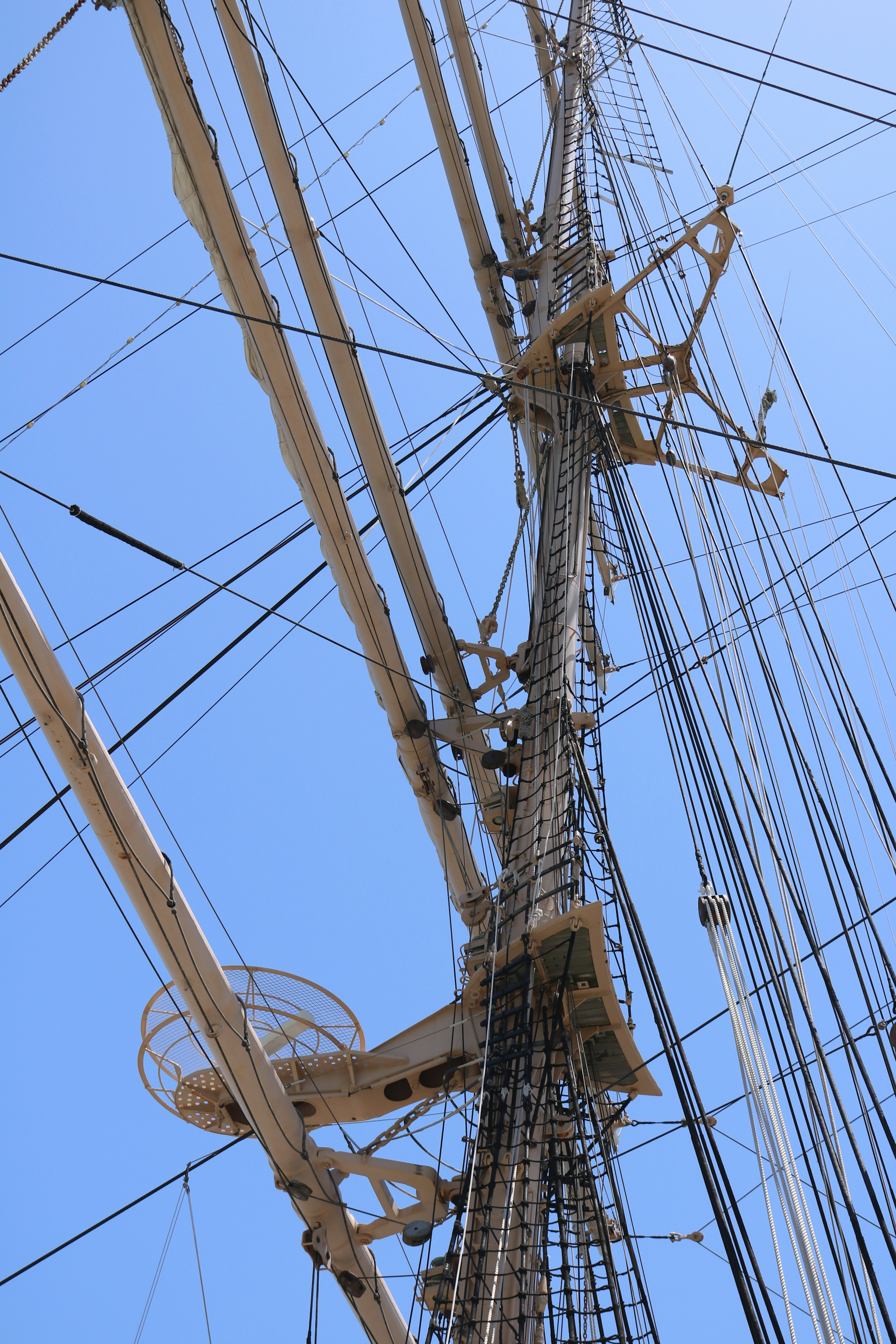 Vue détaillée du mât et des cordages d'un navire sous un ciel bleu