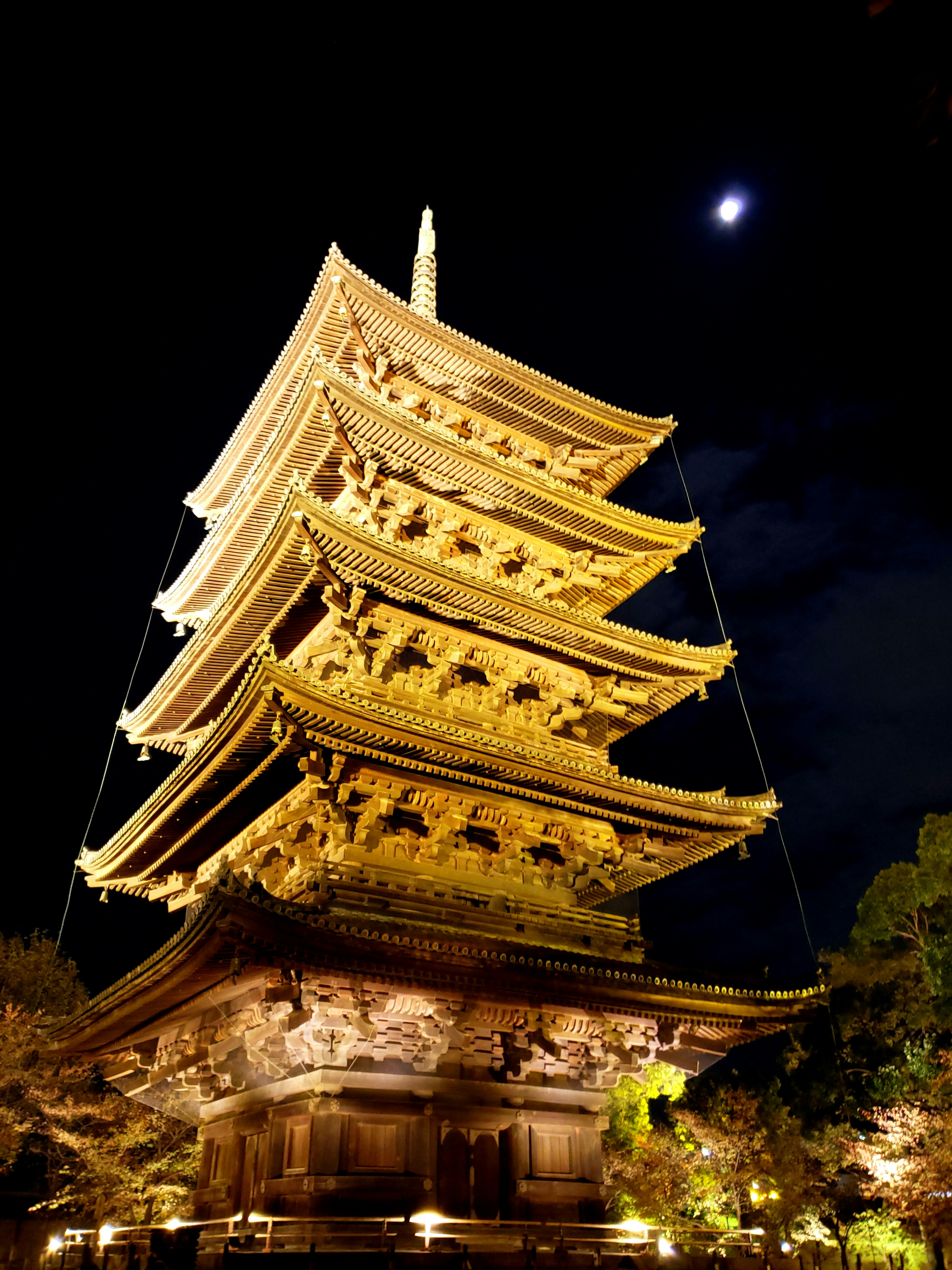 Golden five-story pagoda illuminated at night with moon