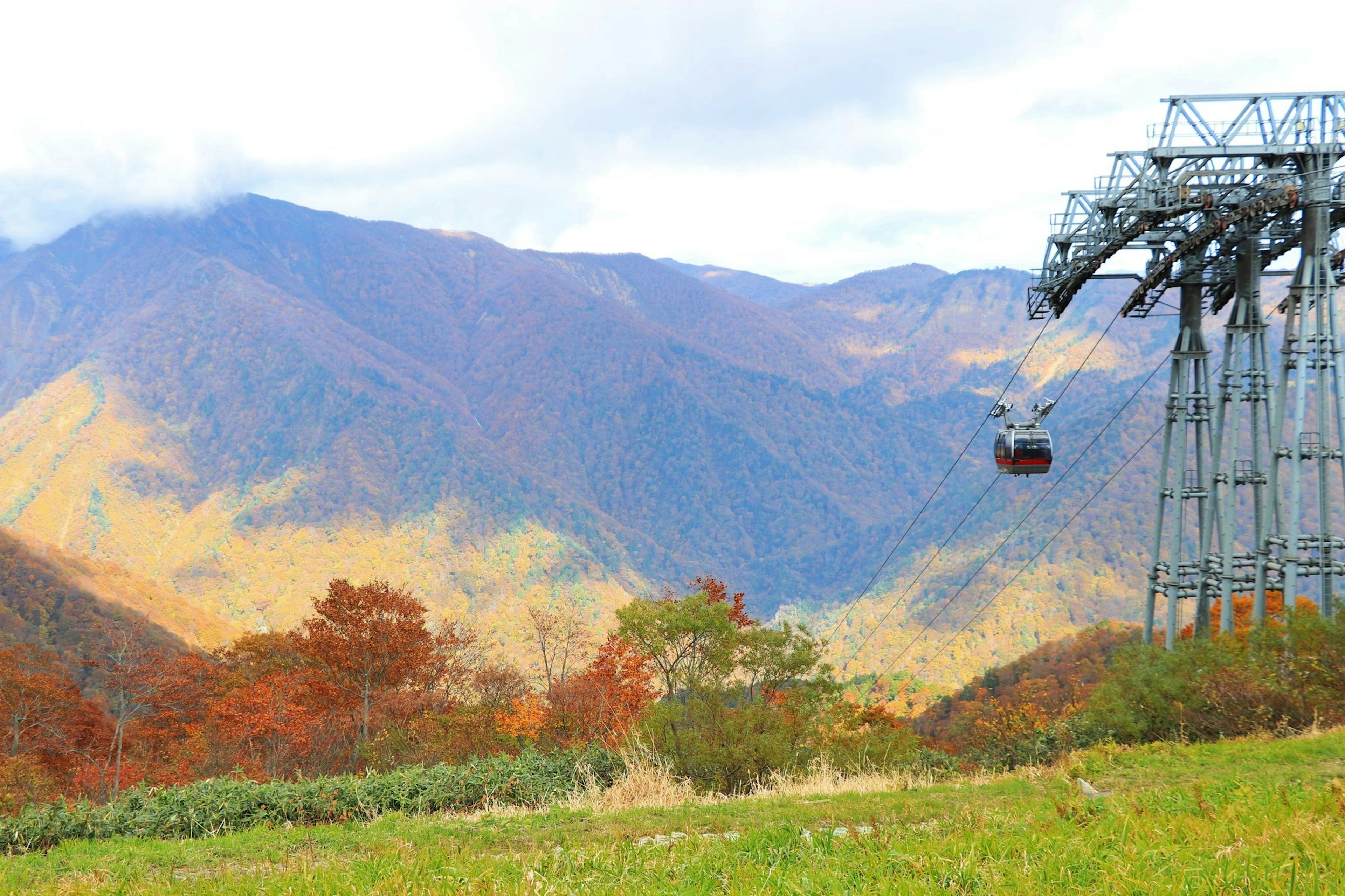 Vista escénica de montañas con follaje de otoño y un teleférico