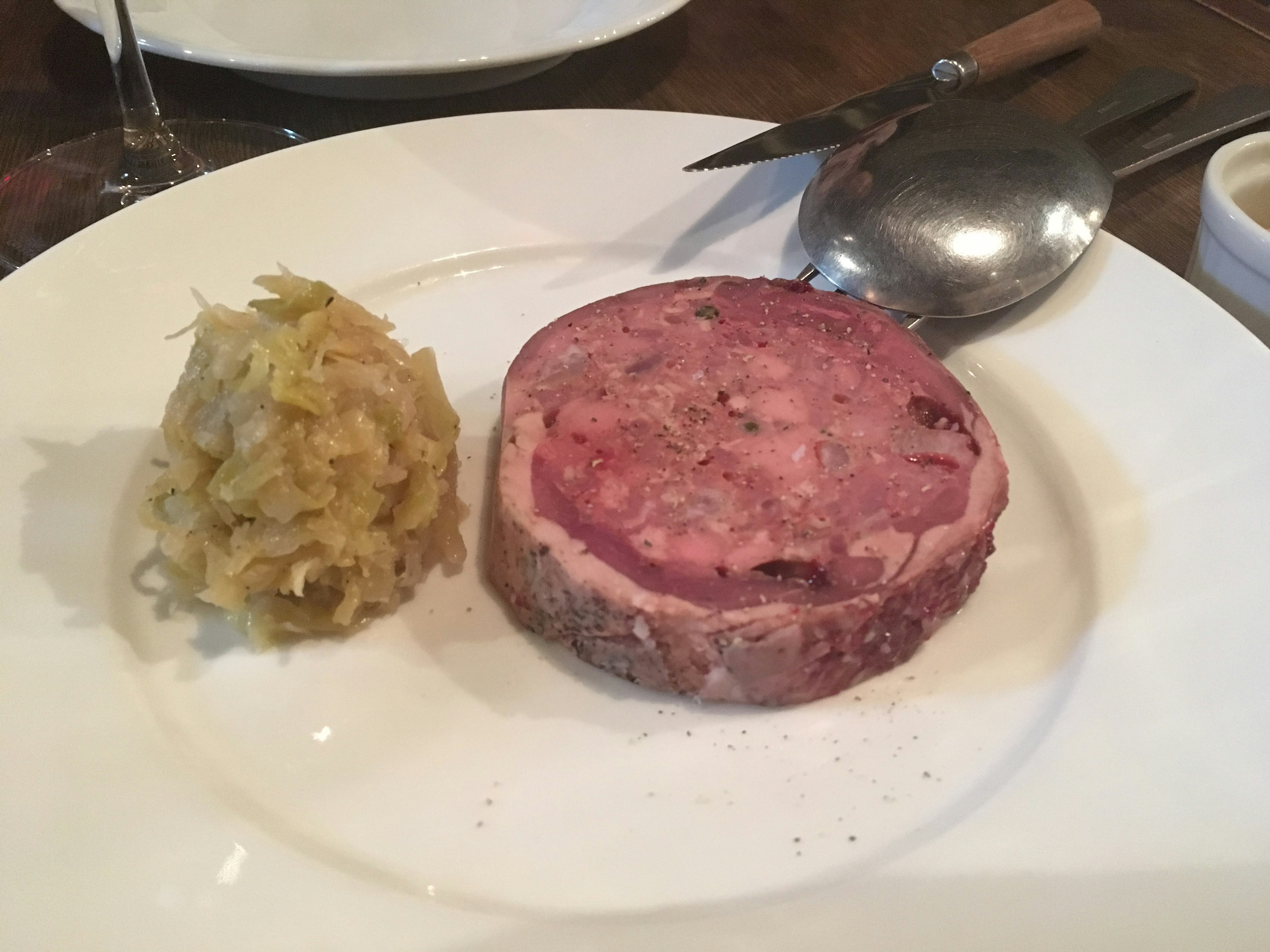 Plate featuring a slice of meat pâté accompanied by a side of cabbage